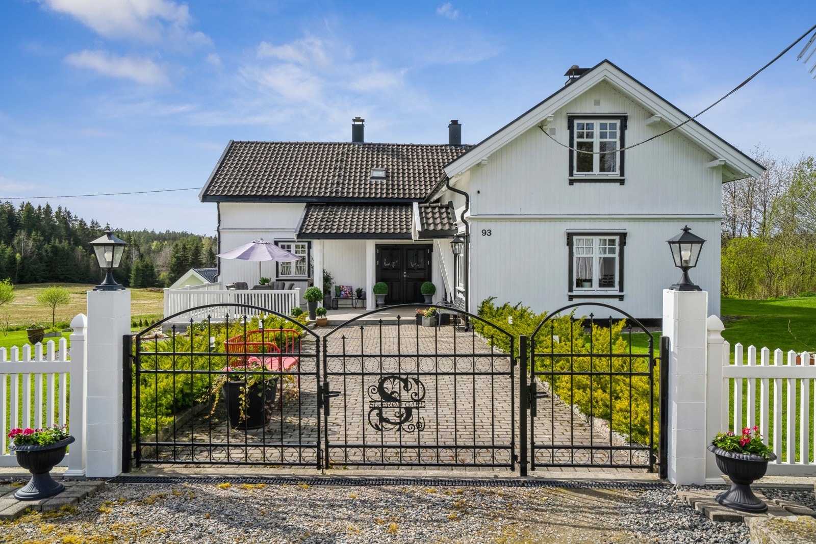 Våningshuset har pent opparbeidet hage og uteareal, avgrenset av hvitmalt gjerde og flotte smijernsporter mot tunet. Galleribilde