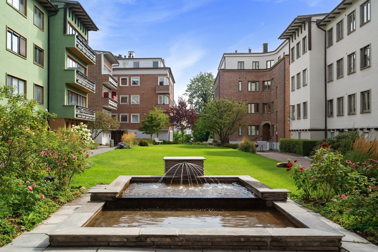 Vakkert, felles gårdsrom med fontene, grøntarealer og beplantning - et hyggelig samlingspunkt for beboerne Galleribilde