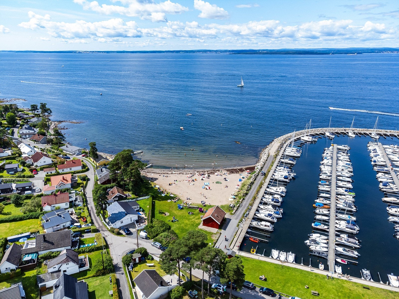 Fra Åsfaret er det kun kort vei å gå ned til sjøen med barnevennlig sandstrand og stor småbåthavn med spisested. Galleribilde