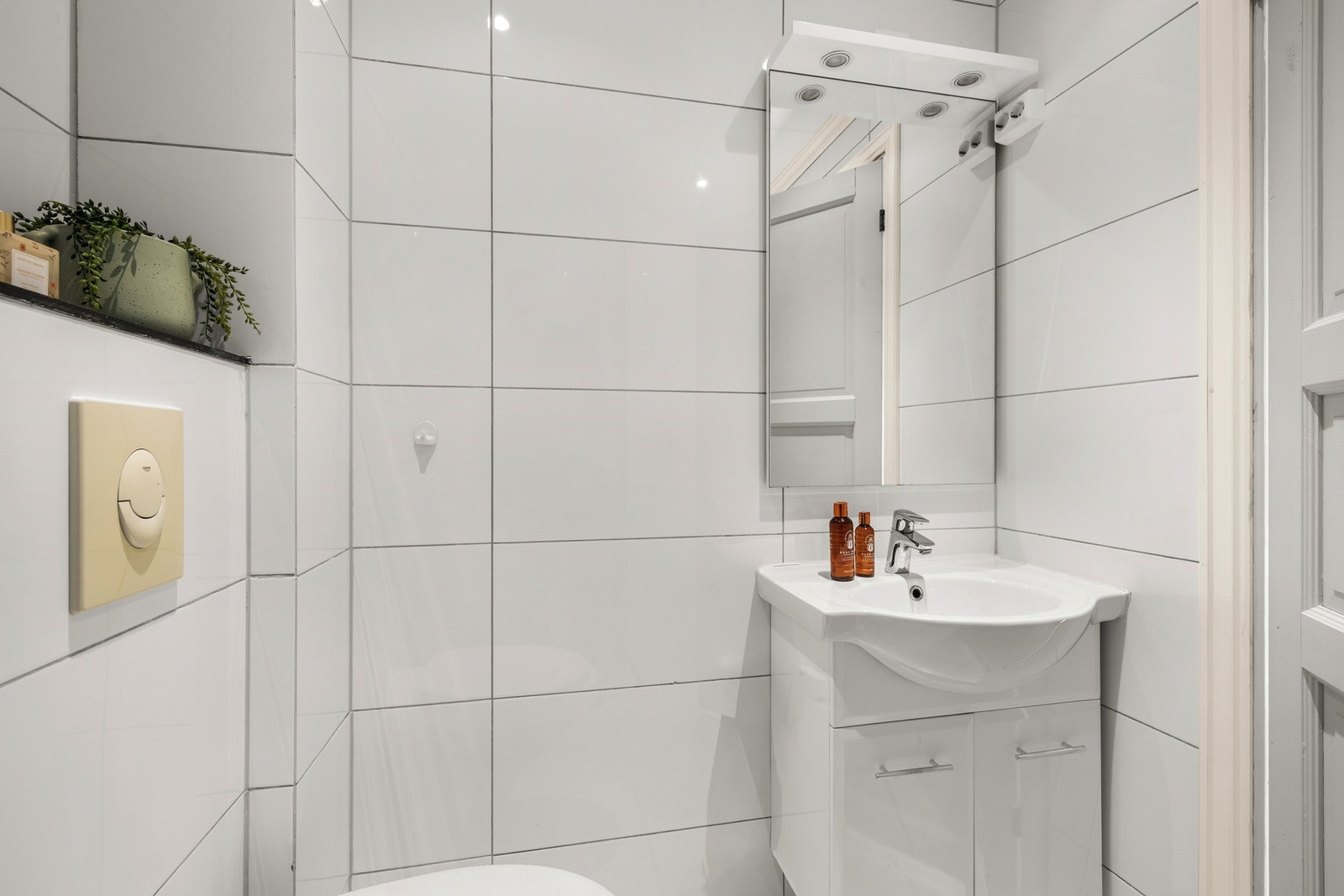 Badet har lyse flater, dusjhjørne, heldekkende servant og vegghengt toalett. Galleribilde