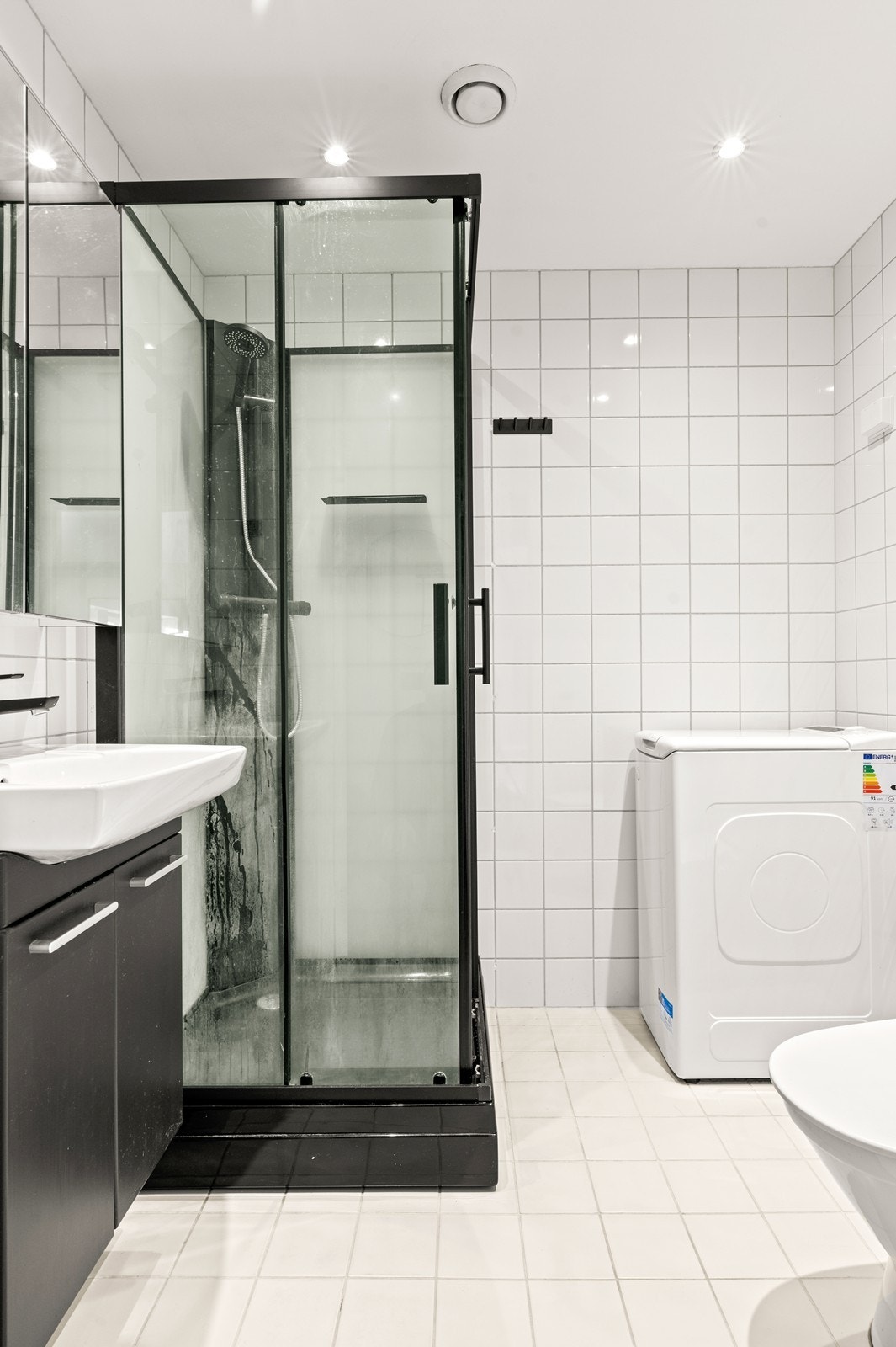 Badet har innredning med nedfelt servant, gulvfestet toalett, dusjkabinett og opplegg for vaskemaskin - Varmekabler på gulvet. Galleribilde