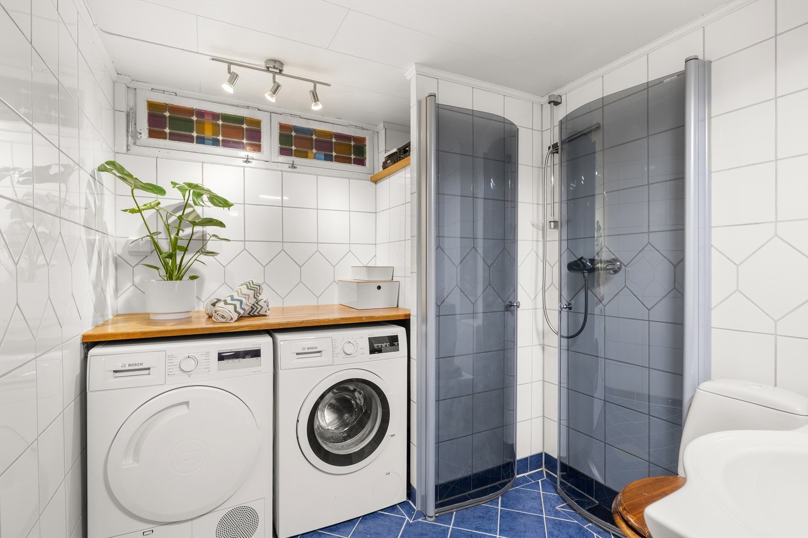 Badet har opplegg for vaskemaskin, tørketrommel, toalett, servant med innredning og dusjhjørne med innfellbare dusjdører. Galleribilde