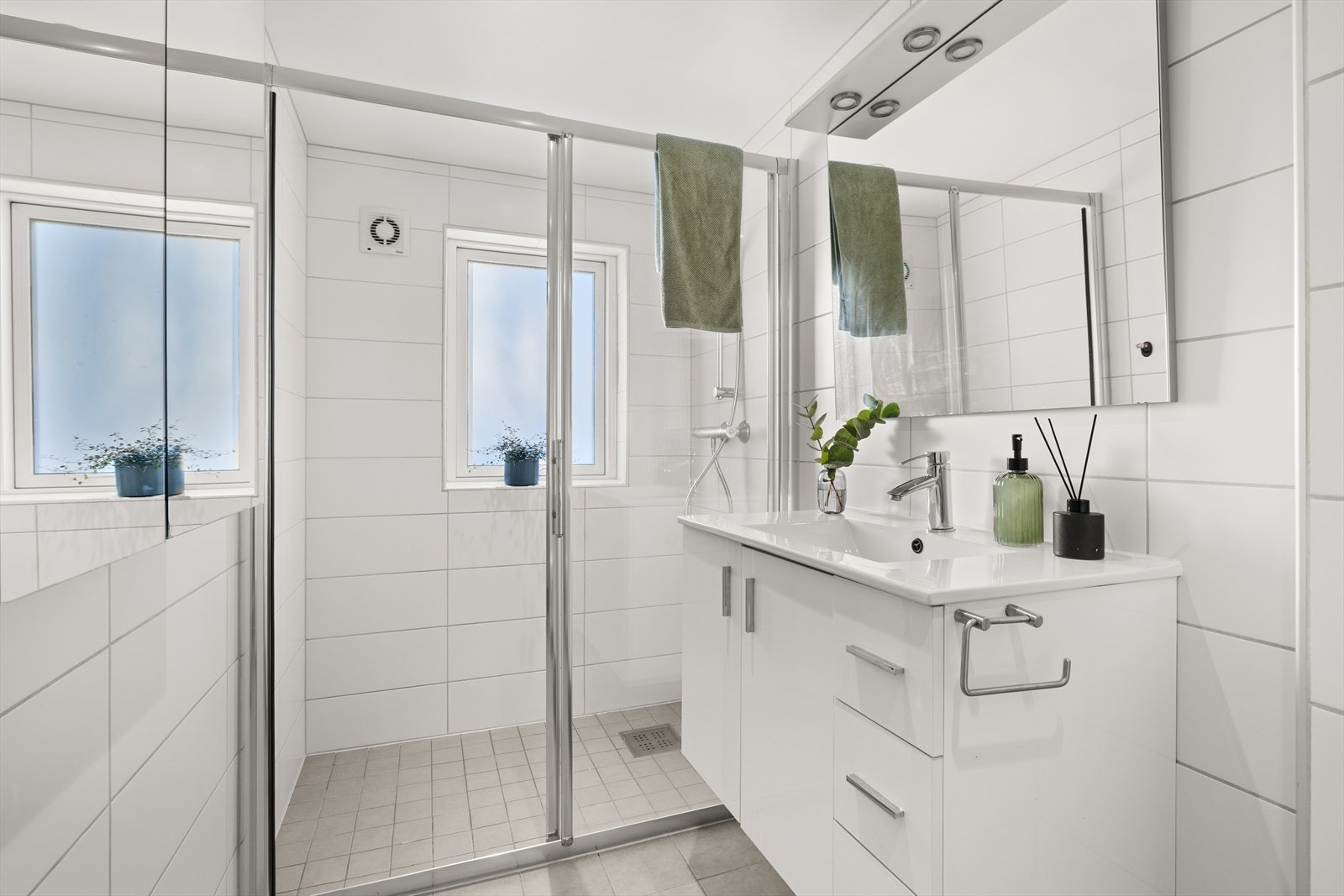 Pent flislagt bad fra 2013 med varmekabler i gulv, romslig dusjsone, servant med innredning og toalett. Galleribilde