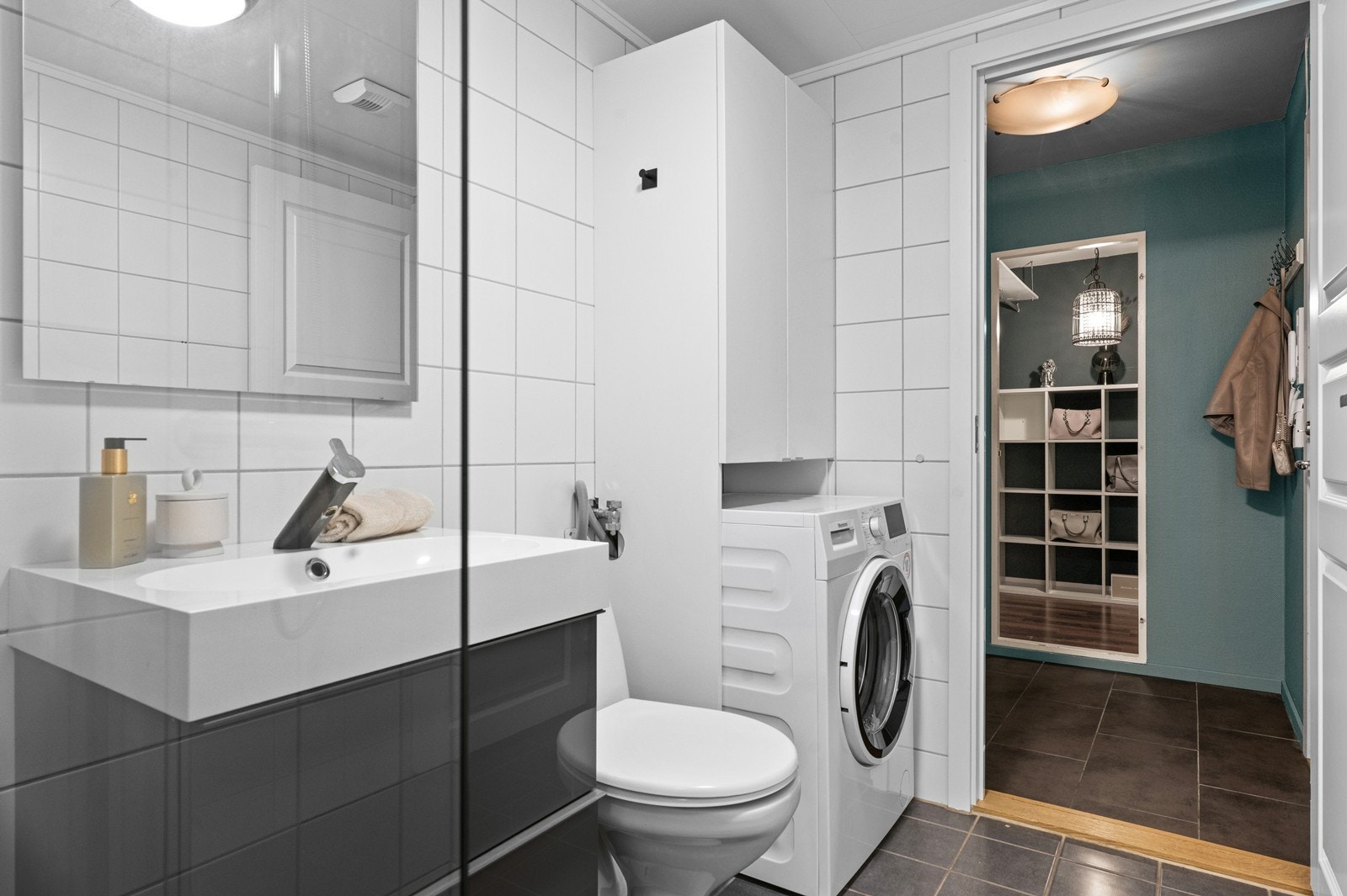Rommet har flislagte overflater, dusjhjørne og praktisk opplegg for vaskemaskin. Galleribilde