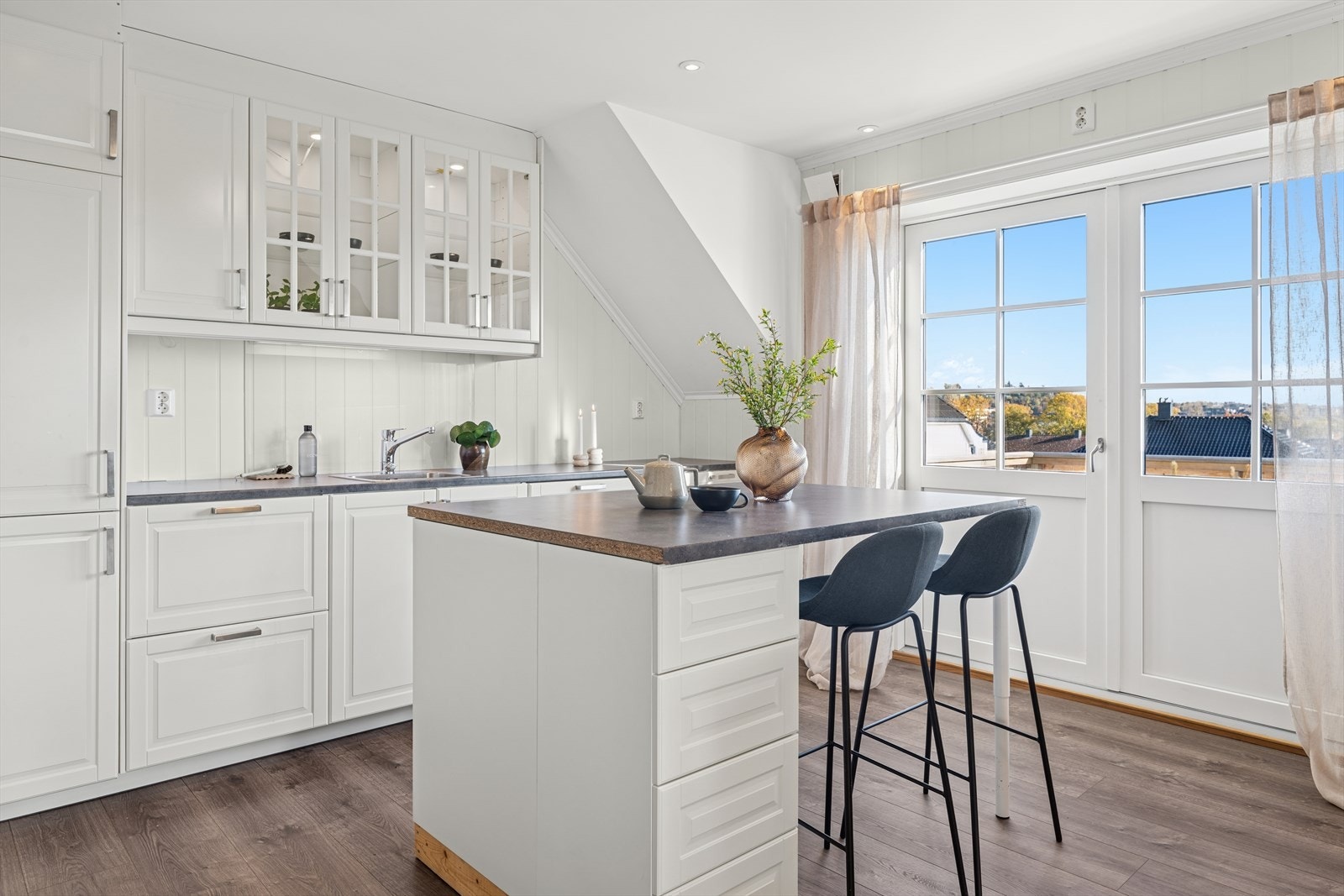 Kjøkkenet ble byttet i 2020 og er tidløst innredet med hvite, profilerte fronter og grå benkeplate i laminat. Galleribilde