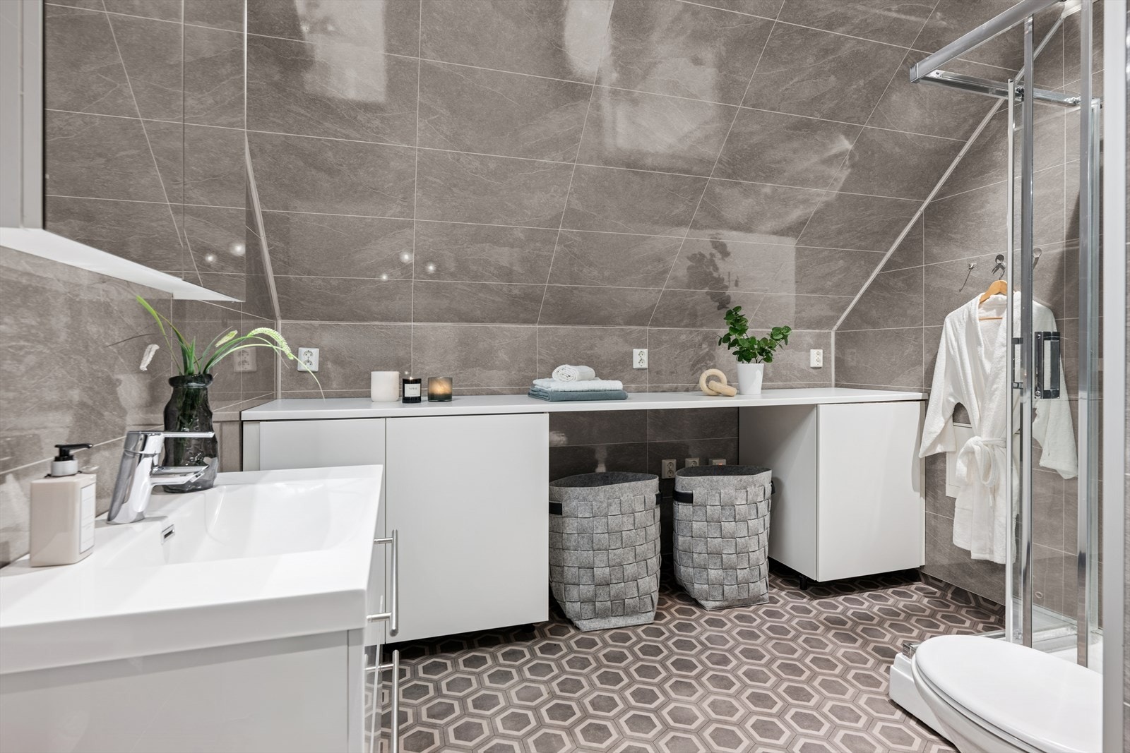 Badet er ellers utstyrt med dusjkabinett, vegghengt toalett og baderomsinnredning med nedfelt servant. I tillegg har man godt med skapplass, egen nisje med opplegg for vaskemaskin og god benkeplass over. Galleribilde