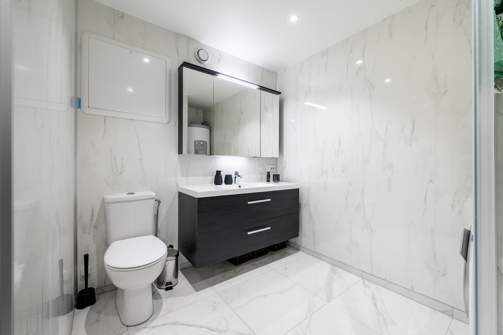 Lekkert bad med flislagt gulv med varmekabler og våtromsplater på vegg. Galleribilde