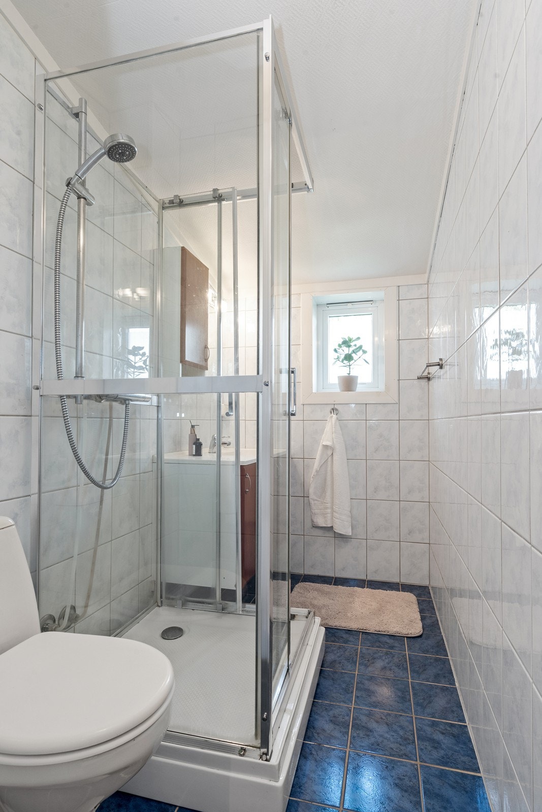 Bad med ukjent høy alder. Rommet har innredning med nedfelt servant, gulvfestet toalett og dusjkabinett. Galleribilde