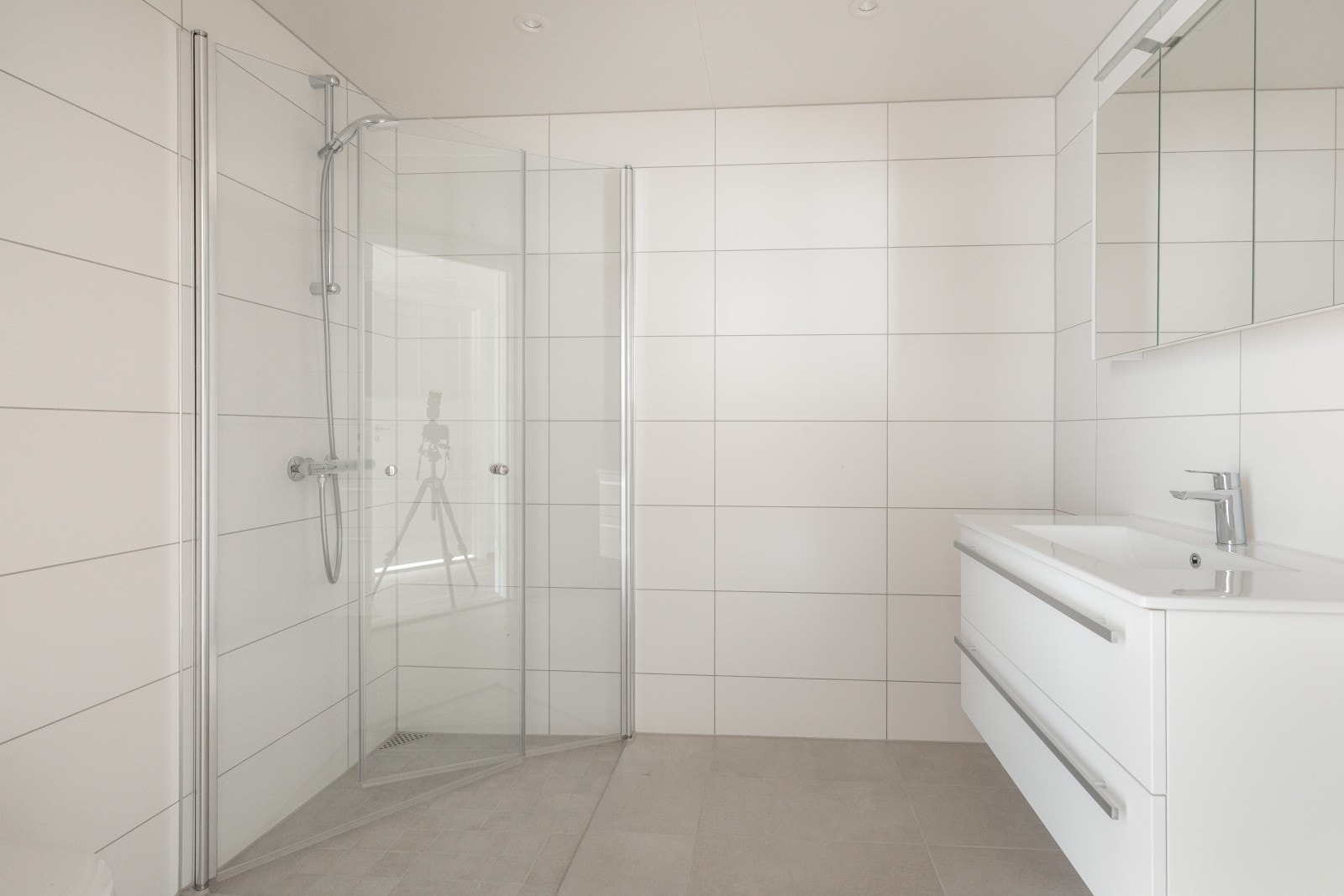 Flott, helfliset bad med gulvvarme og downlights med dimmere. Badet er innredet med veggmontert toalett, dusj på vegg med dusjvegger og servantinnredning med skuffer og speil. Det er balansert ventilasjon. Galleribilde