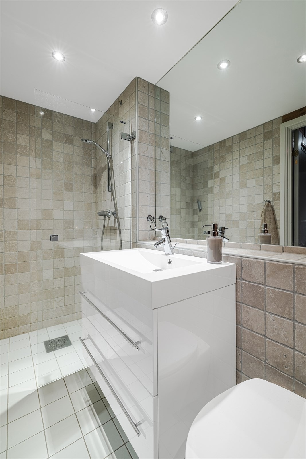 Lyst og moderne bad med stilren design, flislagte vegger og dusjnisje. Galleribilde