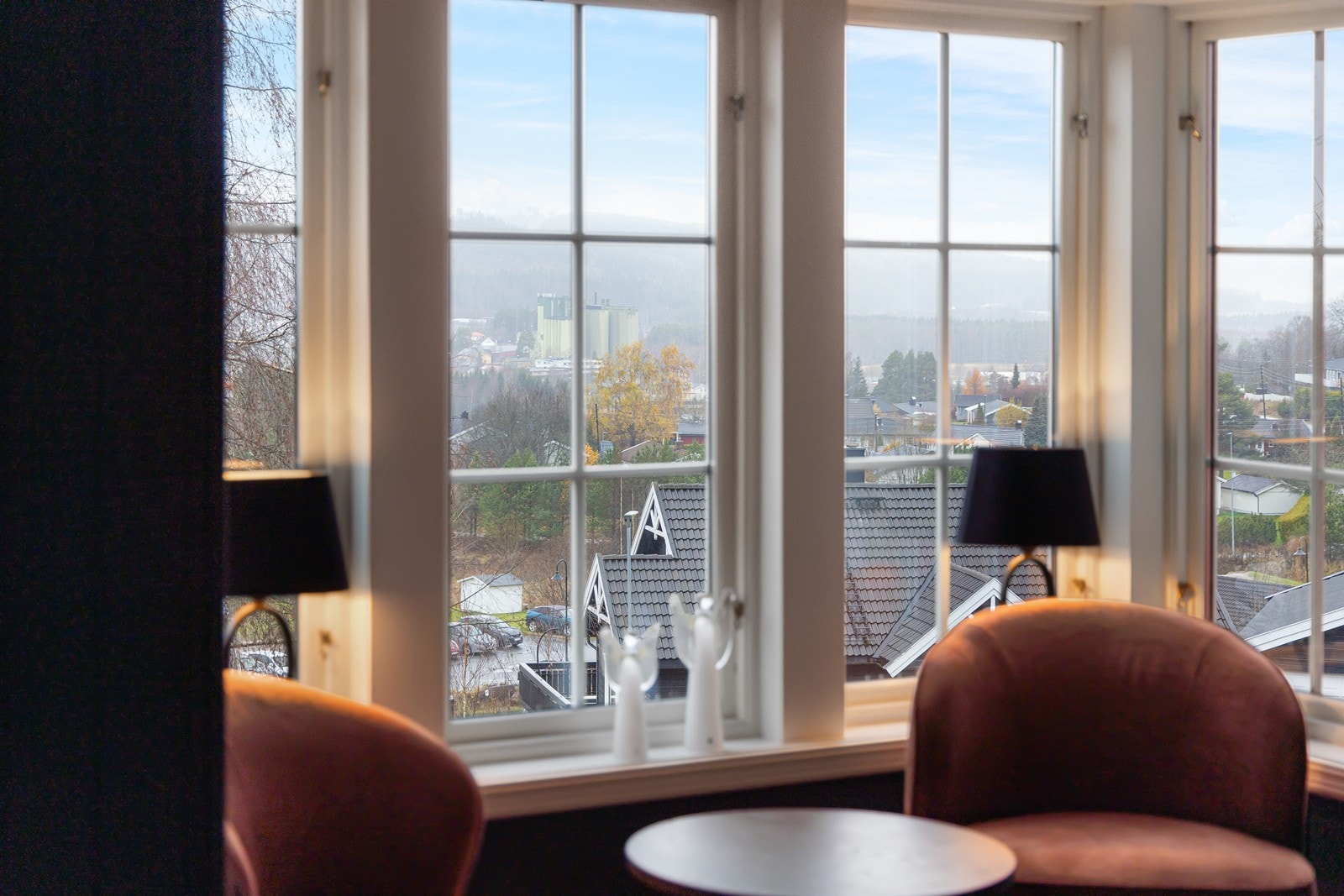 Store vindusflater gir utsyn mot hageområde og nærliggende bebyggelse. Galleribilde