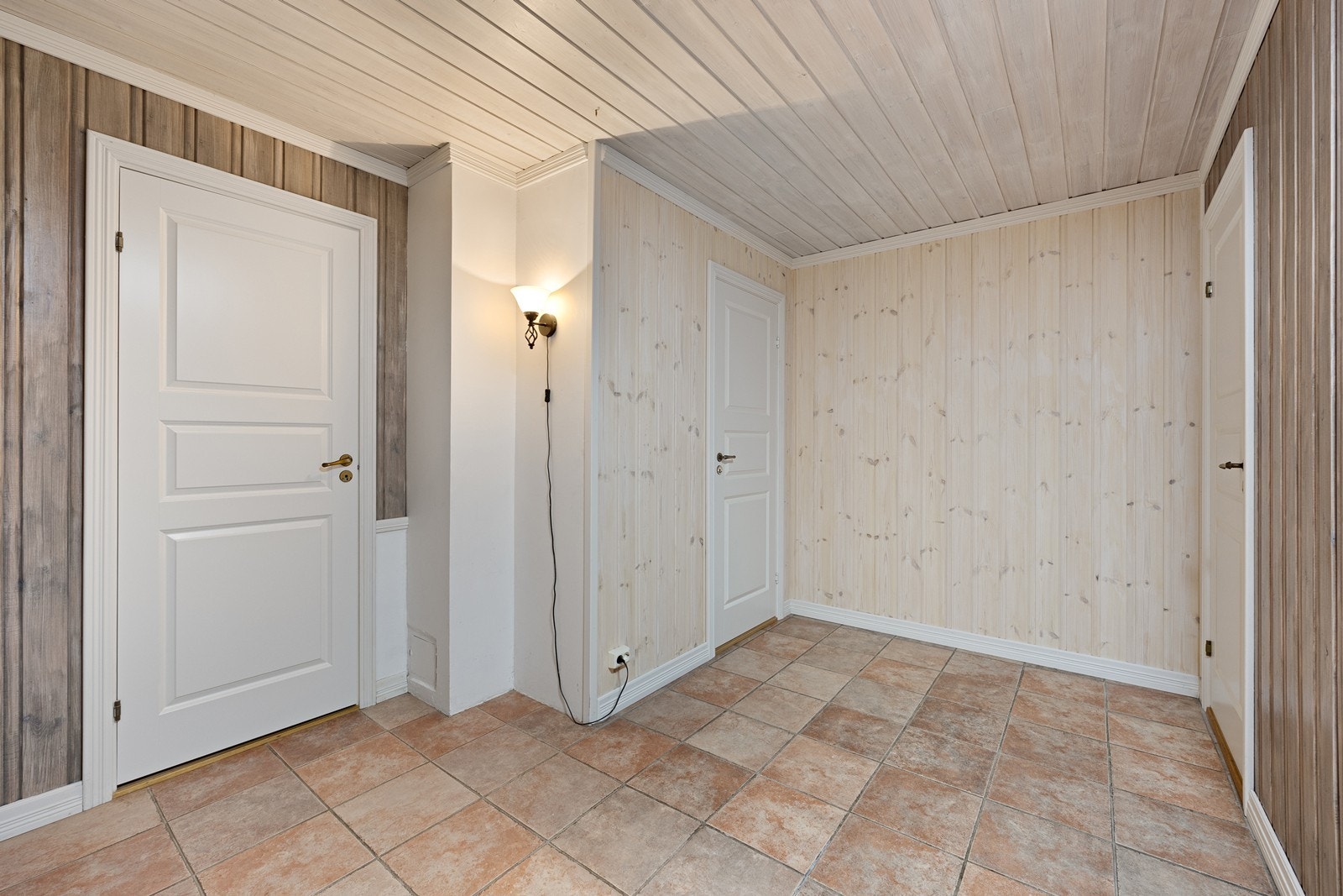 Fliser på gulvet og lys panel på veggene skaper et harmonisk uttrykk i entréen. Galleribilde