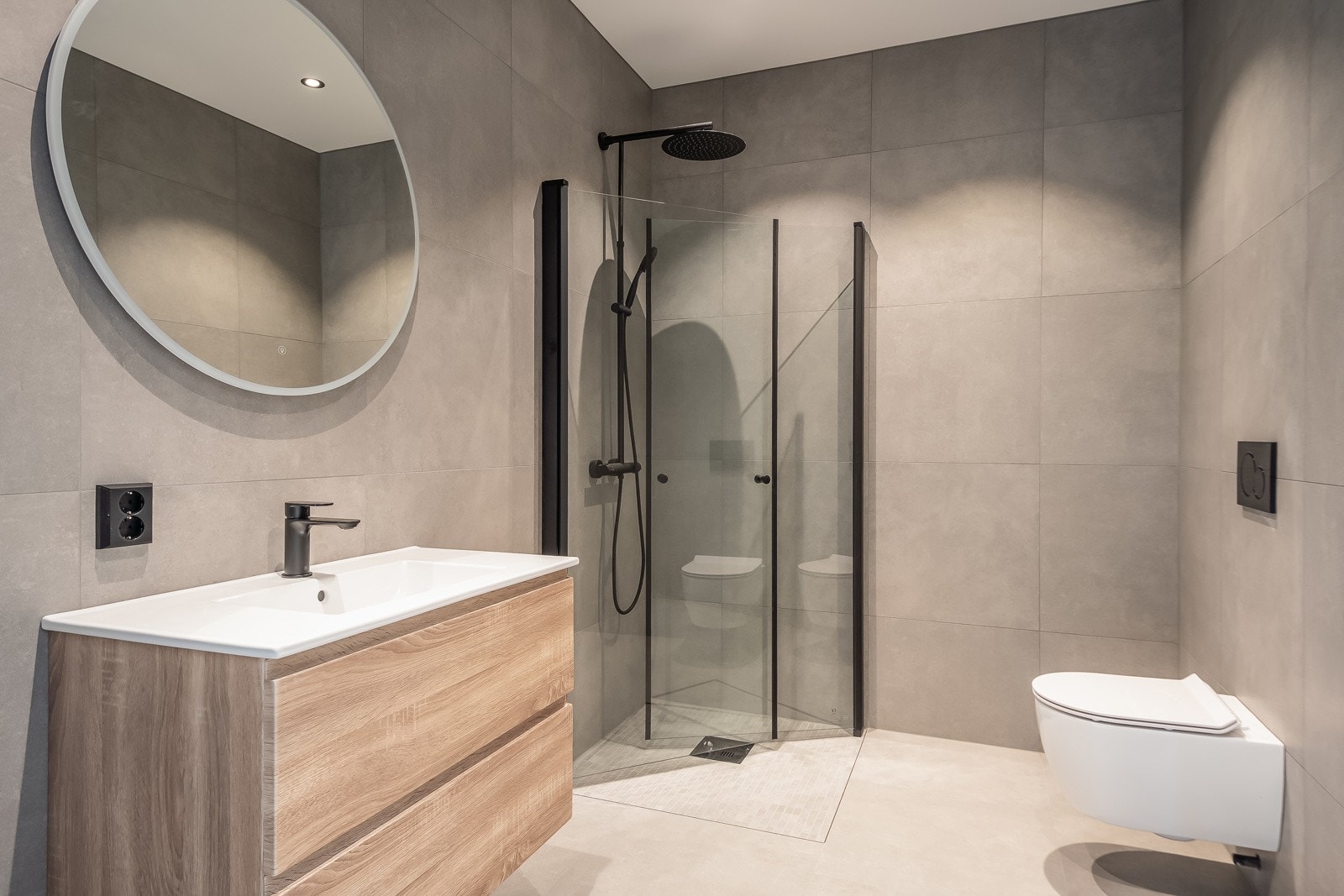 Delikat bad på 5,8 kvm med store fliser på 60x60 cm. Innskyvbare glassdører i dusjen med regnfallsdusj og vegghengt wc. Stilige og gjennomførte detaljer og flott innredning. Galleribilde