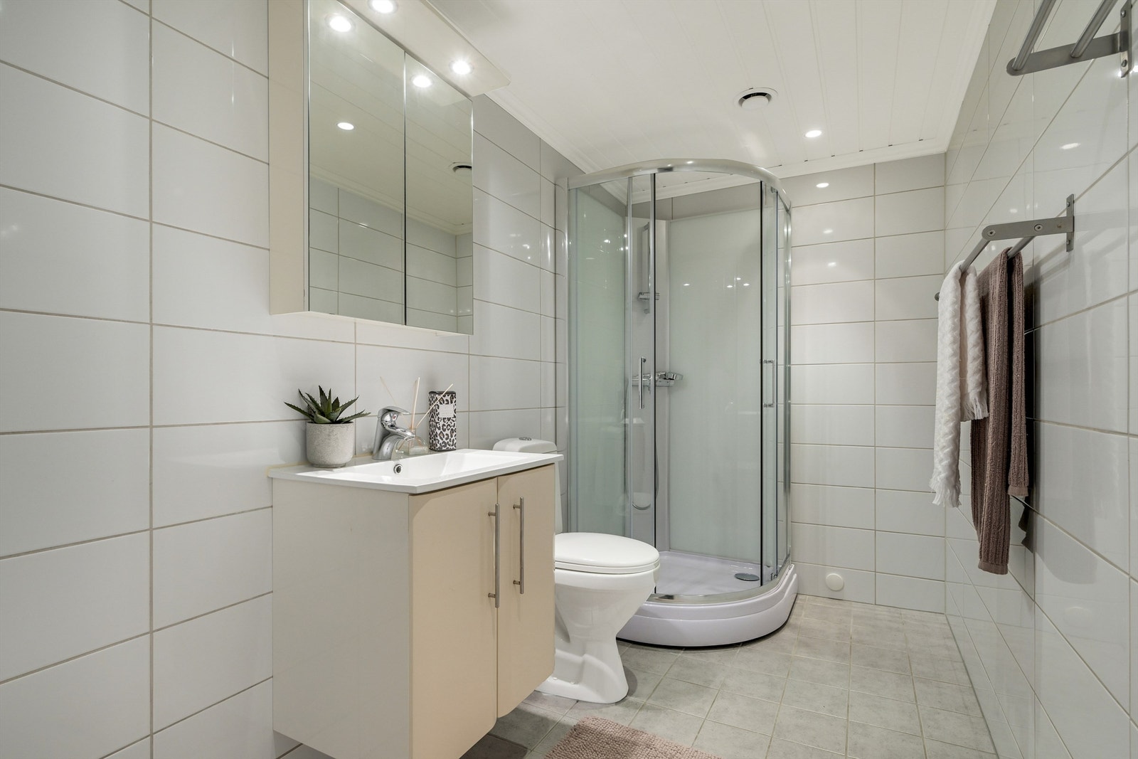 Lyst og pent bad med flislagte vegger og gulv. Rommet har elektriske varmekabler i gulvet og spotter i taket. Galleribilde