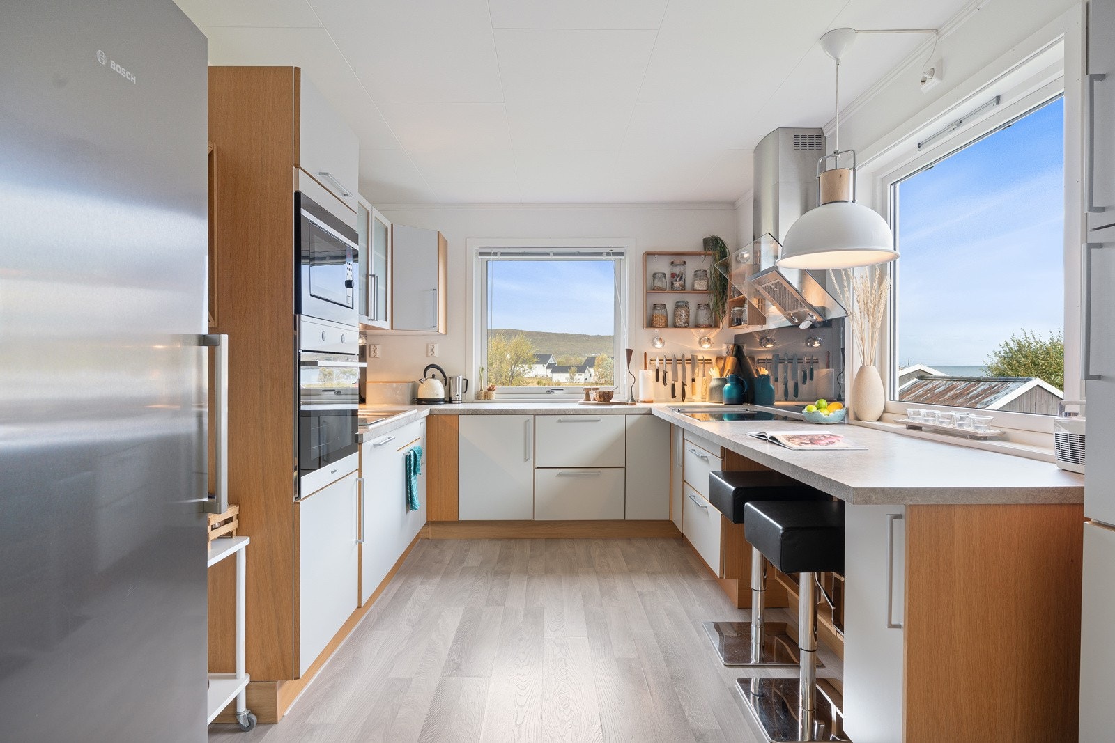 Lys og tidløst kjøkkeninnredning fra HTH med glatte fronter, laminat benkeplate og barløsning. Galleribilde