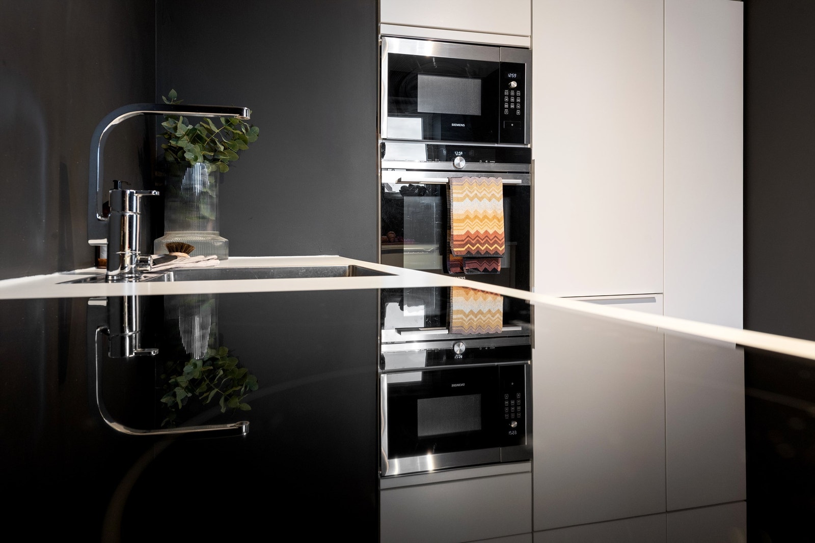 Moderne kjøkken med stilrent design og integrerte hvitevarer. Perfekt for matlaging og underholdning i et elegant hjem. Galleribilde