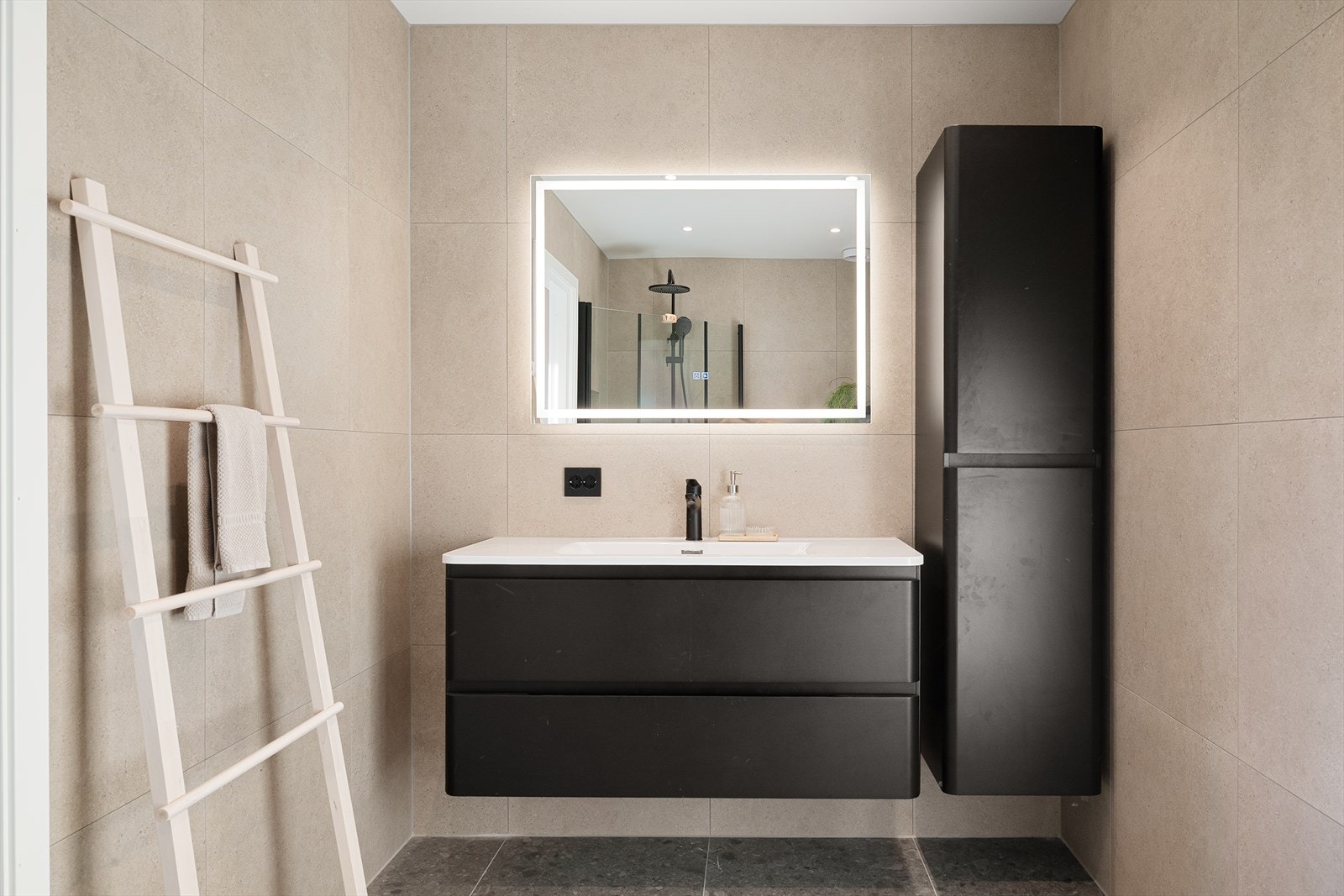 Det er helfliset i nøytrale farger, har varmekabler i gulvet og er innredet med vegghengt toalett, servant med underskap, speil og dusjhjørne. Galleribilde