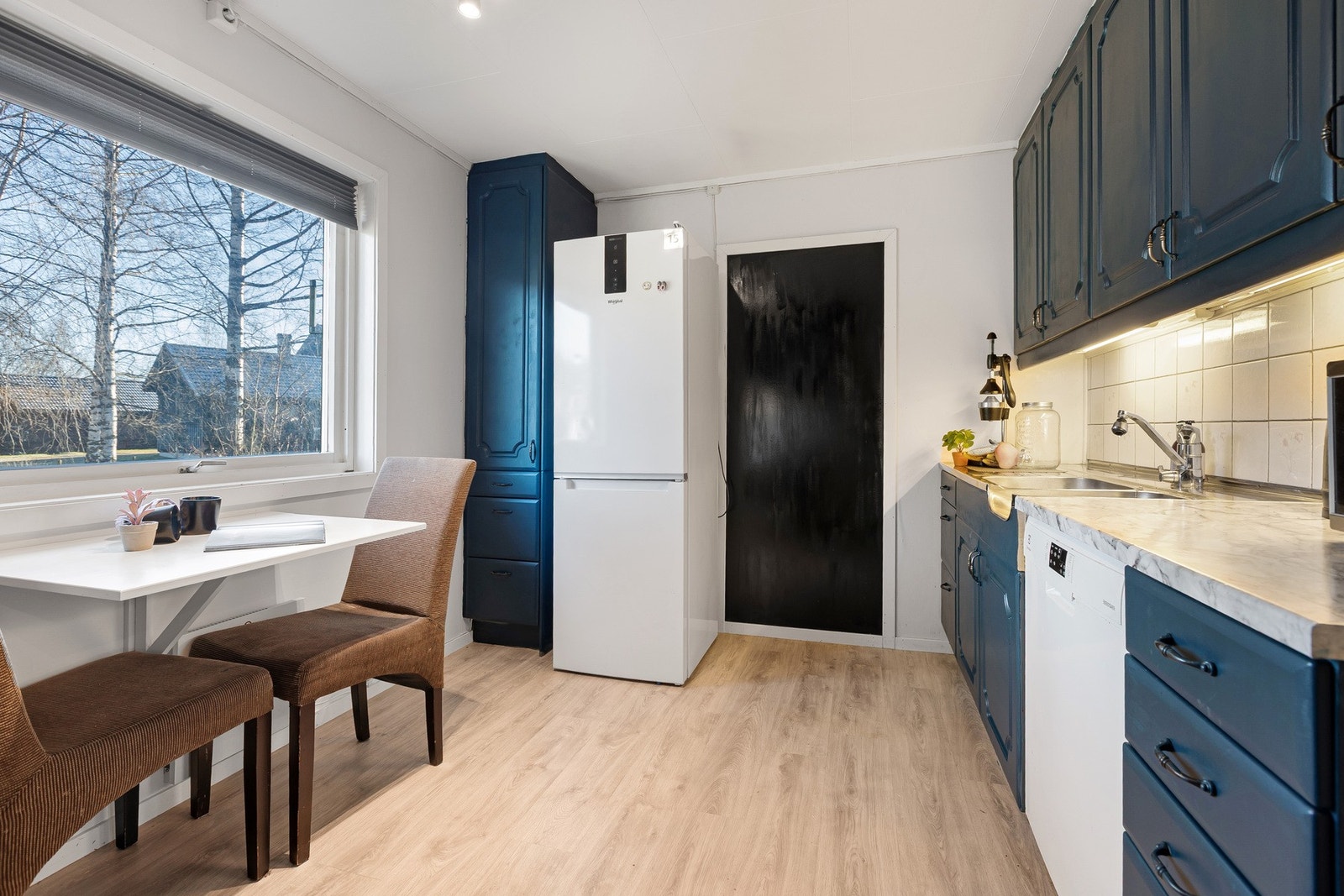 Lyst kjøkken med plass til stort kjøleskap og praktisk spiseplass for to. Galleribilde