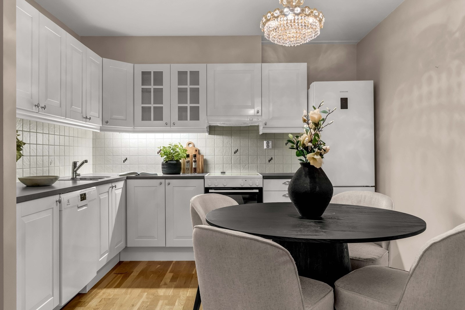 Kjøkkenet har lyse, profilerte fronter og frittstående hvitevarer. Galleribilde