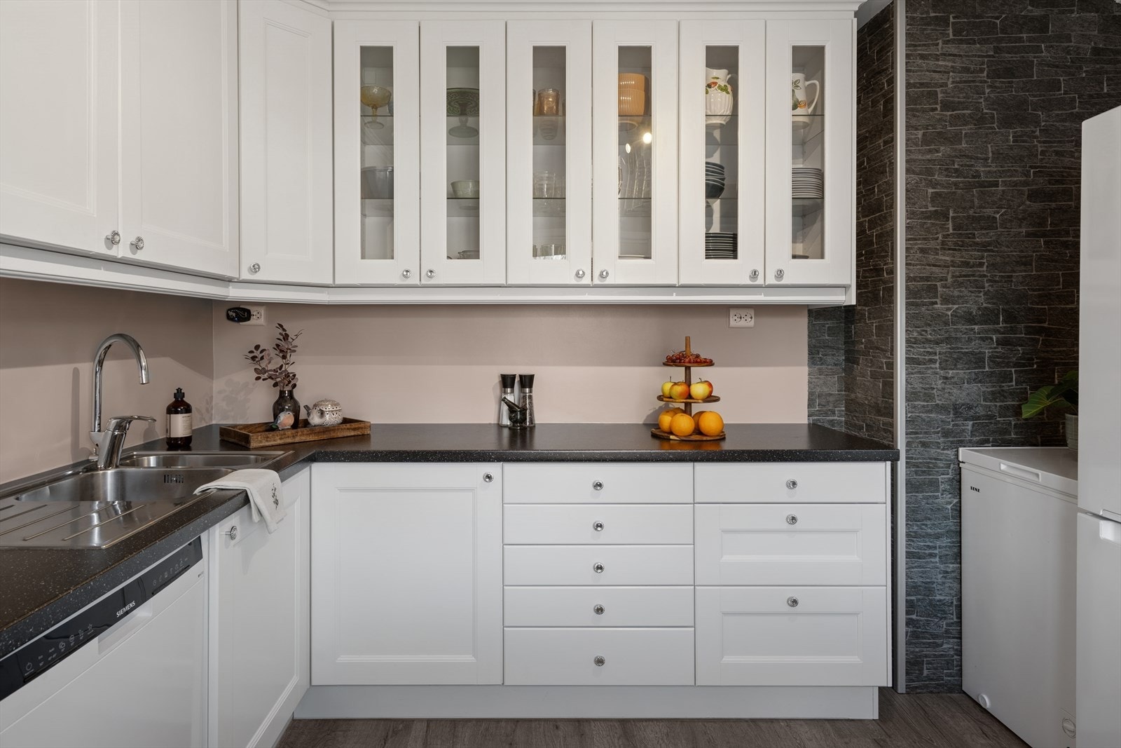 Kjøkkeninnredning med hvite profilerte fronter med tre fronter i glass på overskap. Galleribilde