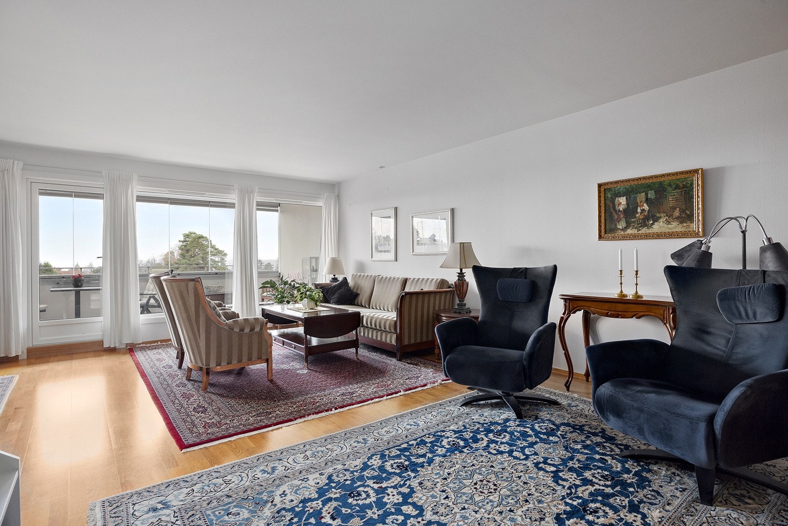 Leiligheten har en romslig stue med store vindusflater som slipper inn naturlig lys til hele rommet Galleribilde