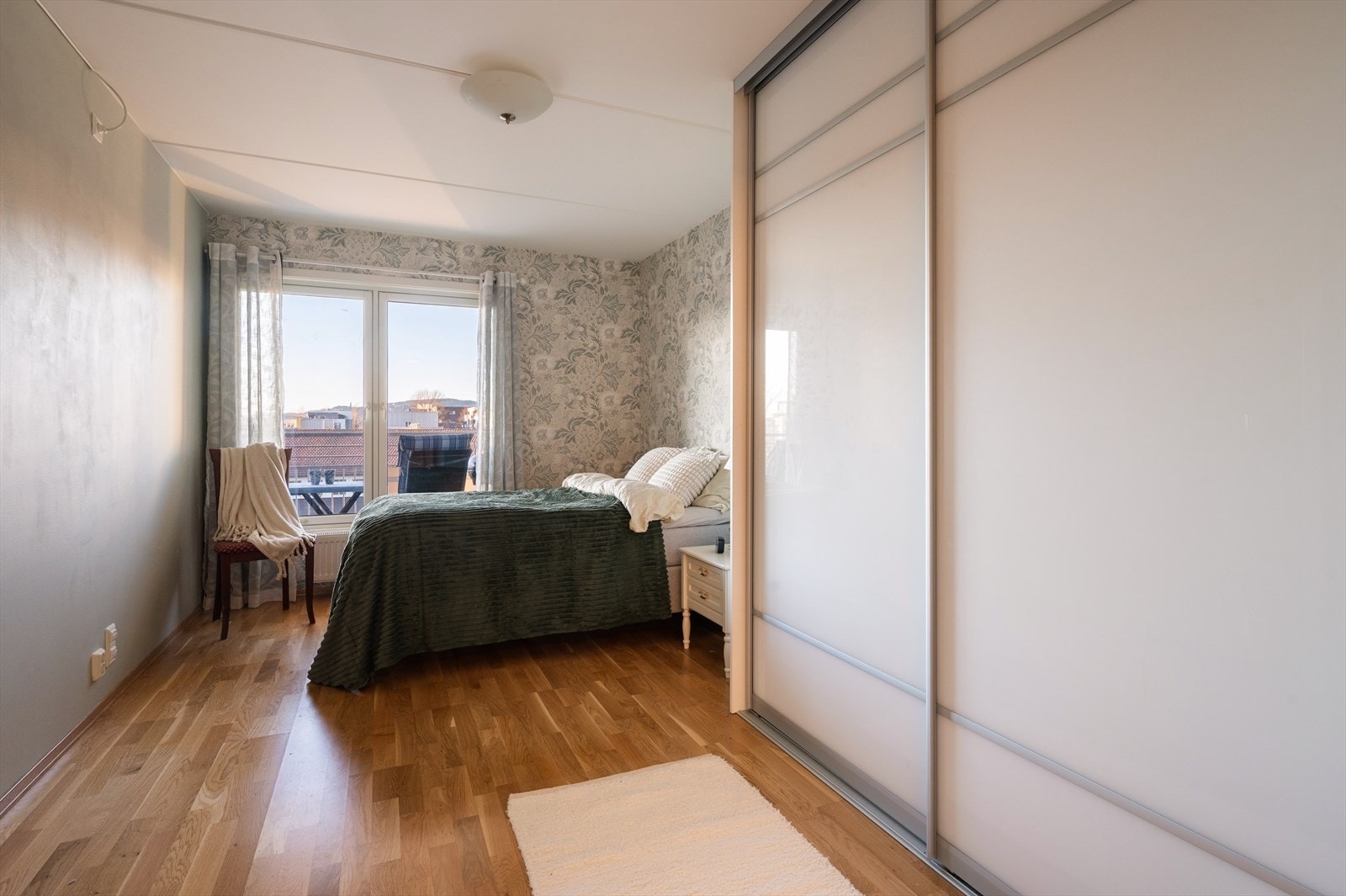 Romslig og innbydende hovedsoverom med flott tapet på vegg og nymalte veggflater i matchende fargepalett. Galleribilde