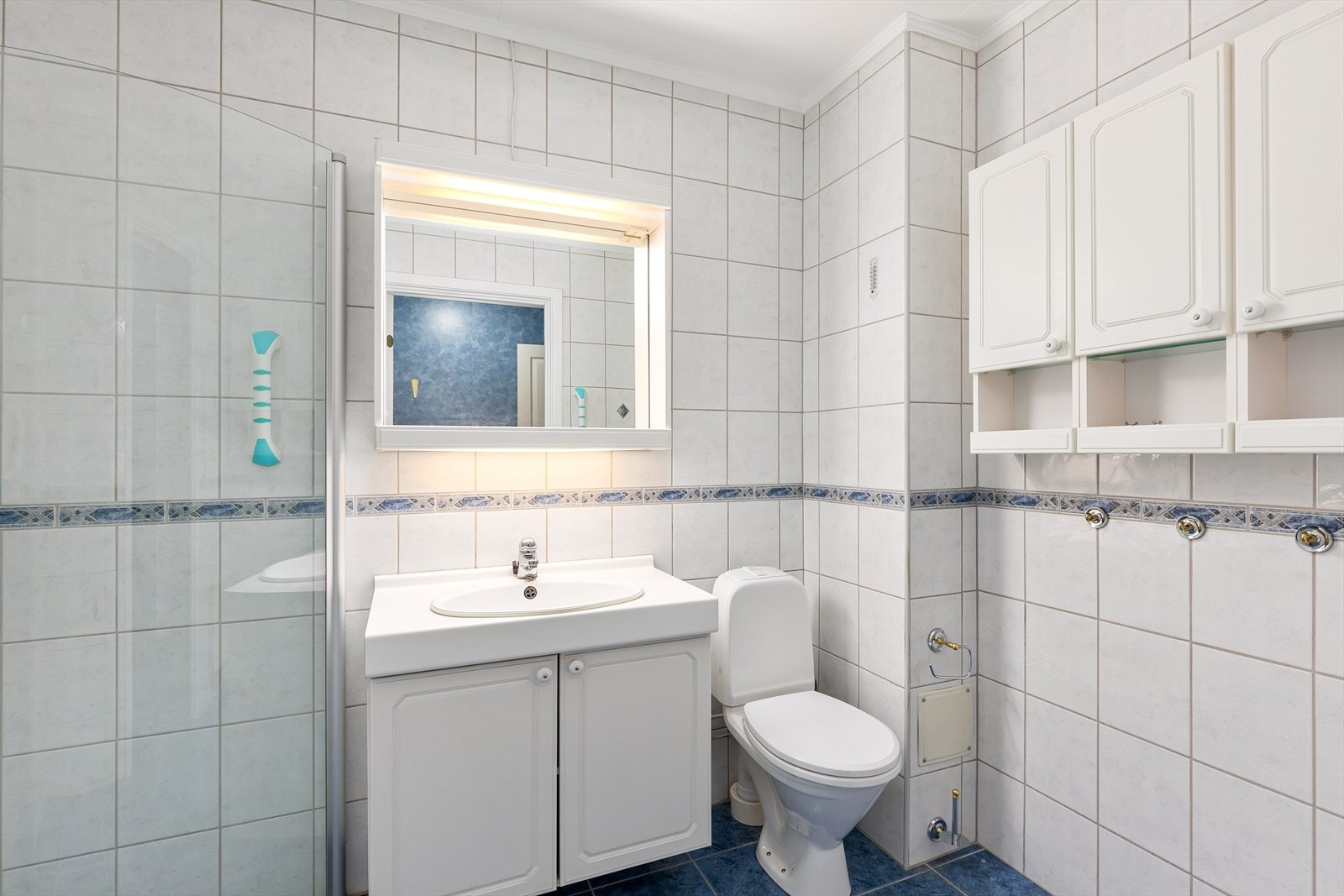 Badet er innredet med servant nedsenket i innredning, dusjhjørne med innfellbare glassdører og toalett Galleribilde