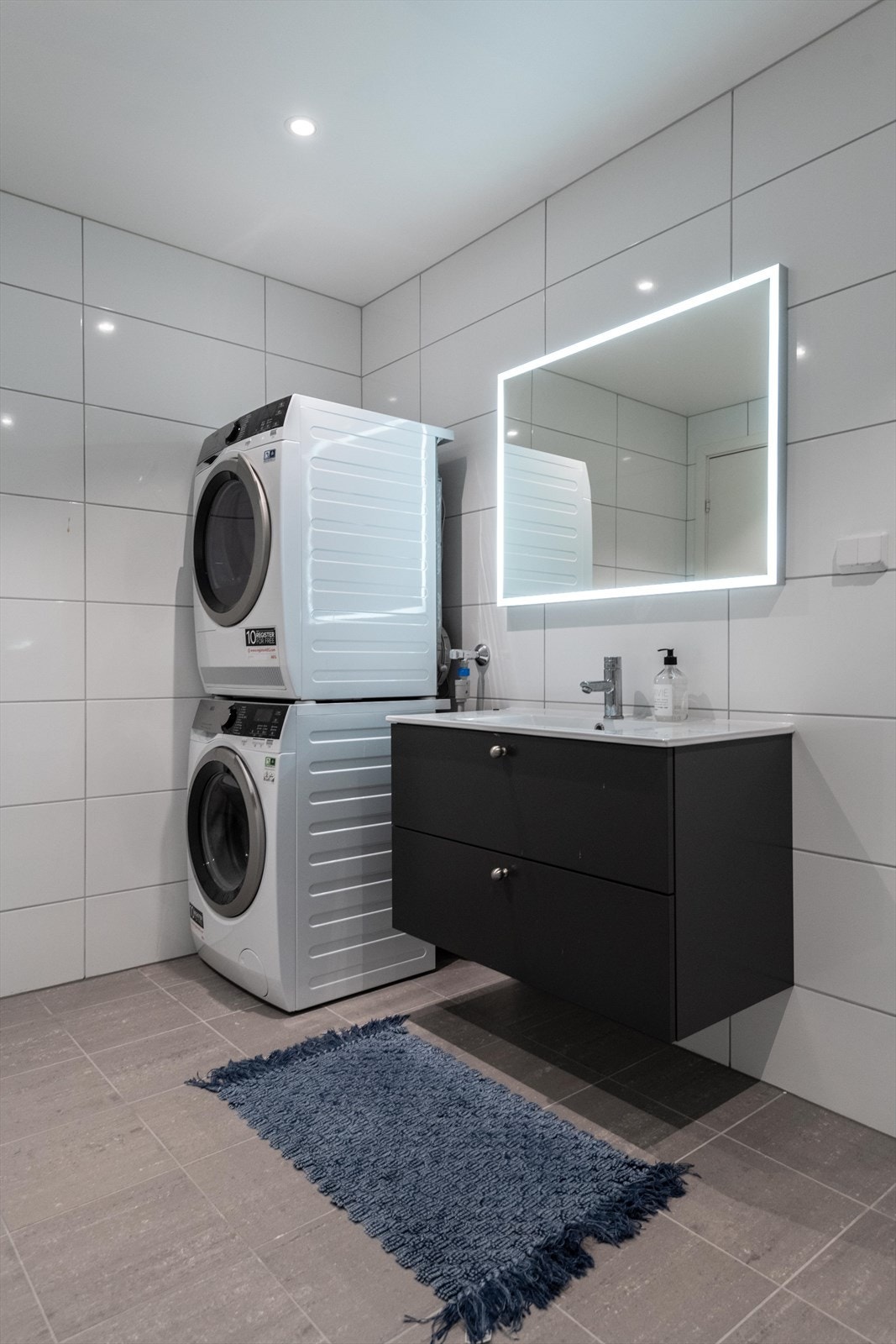 Innredet med nedfelt servant, veggfestet toalett, dusjnisje og opplegg for vaskemaskin. Galleribilde