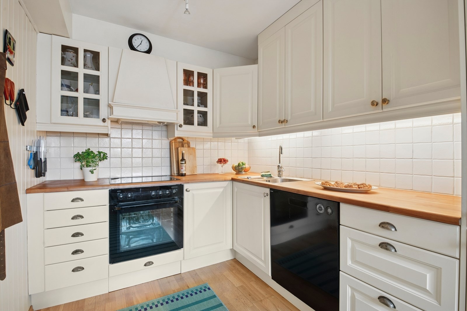 Kjøkkenets innredning har profilerte fronter, enkelte glassfronter i overskap, heltre benkeplate med nedfelt oppvaskkum, fliser over benk, belysning under overskap og ventilator. Galleribilde