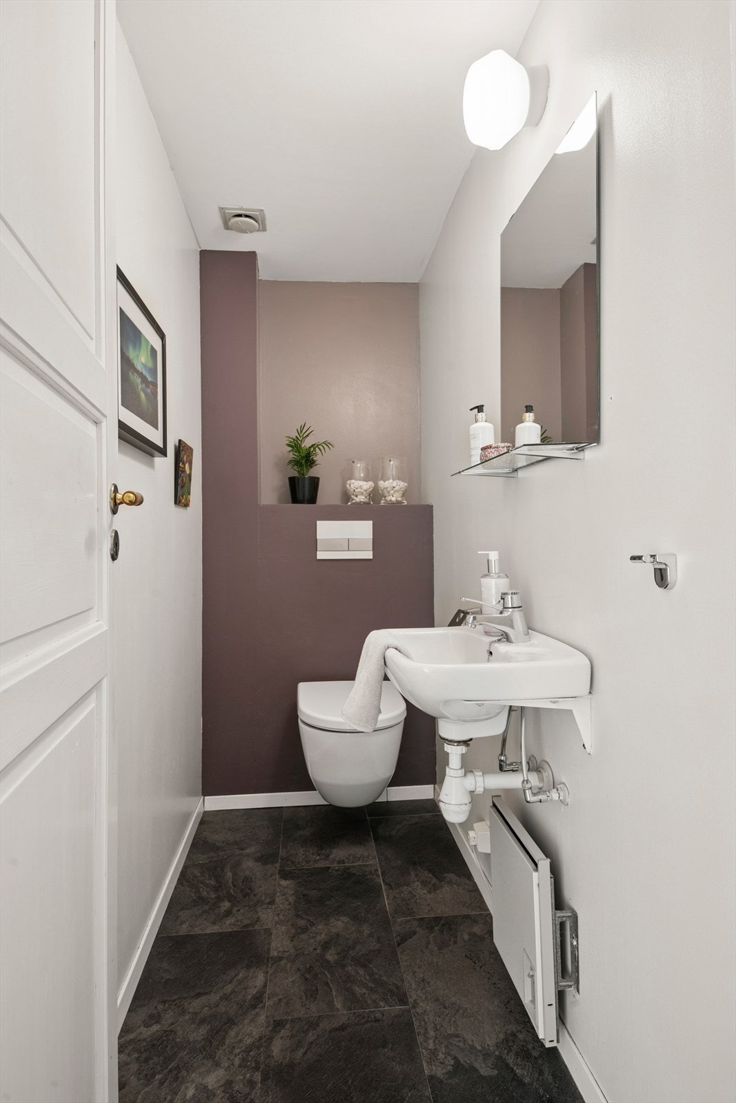 I 1. etasje har boligen et separat toalettrom med veggmontert toalett, enkel servant og speil med overliggende lys. Galleribilde