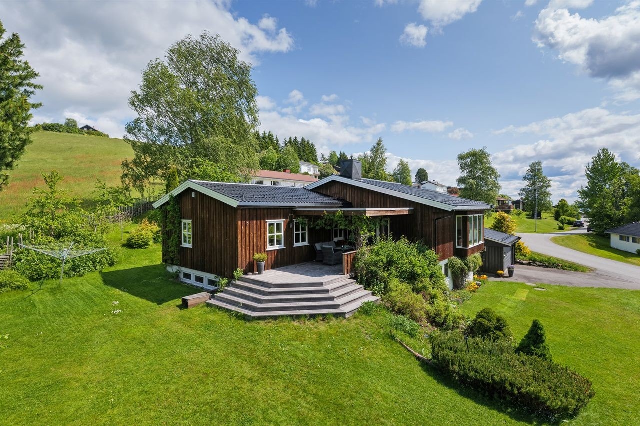 Boligen har garasje med leddport, asfaltert oppkjørsel og stor hage med flere uteplasser. Galleribilde