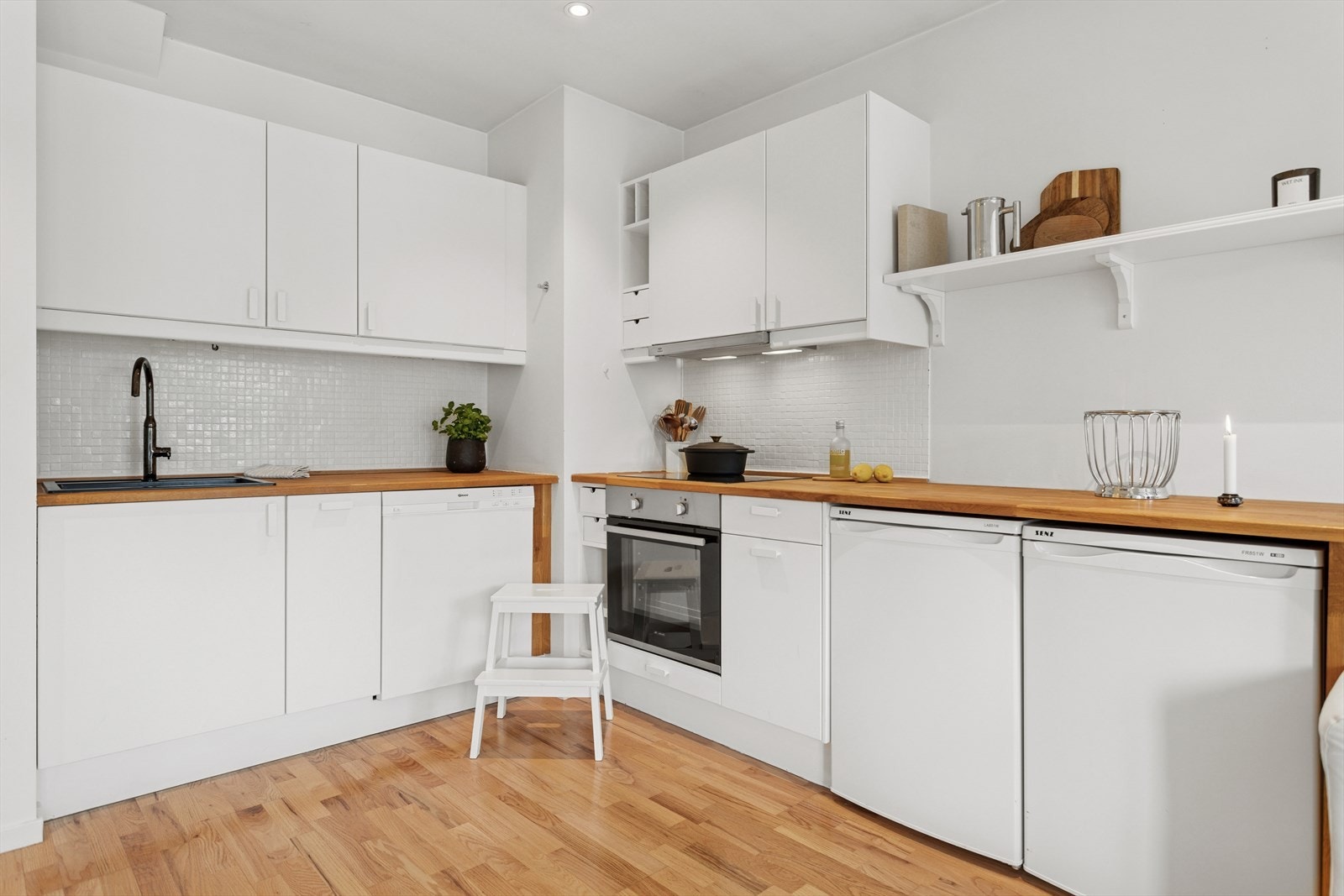 Stilrent kjøkken med integrerte hvitevarer som oppvaskemaskin, platetopp, stekeovn og ventilator. Galleribilde