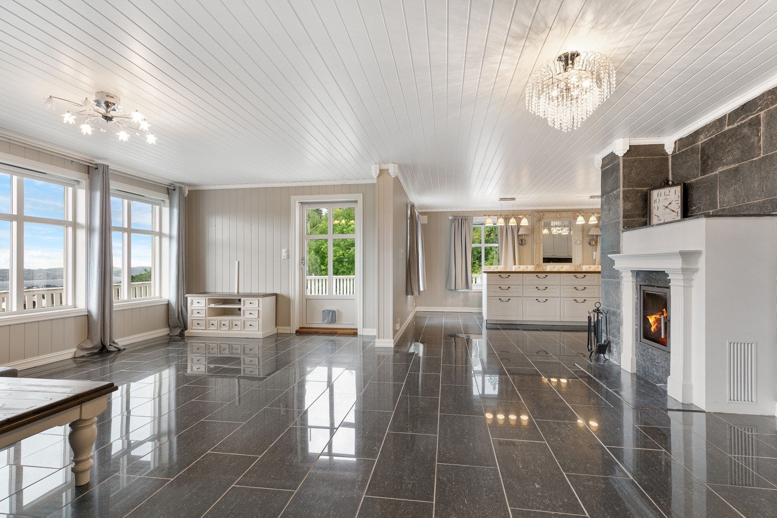 Stue med fliser på gulv og peisovn med glassdør Galleribilde