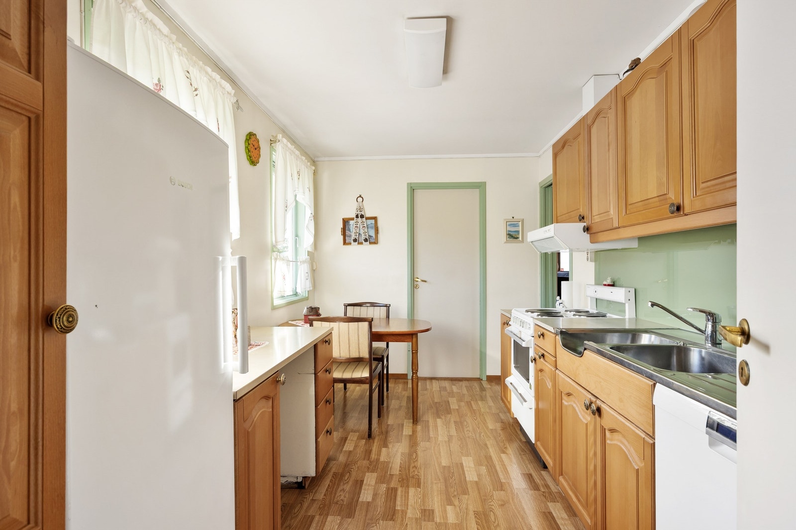 Kjøkkenet ligger mellom de to entréene. Praktisk på sommerstid for å utnytte de fine uteområdene på fremsiden av boligen. Galleribilde