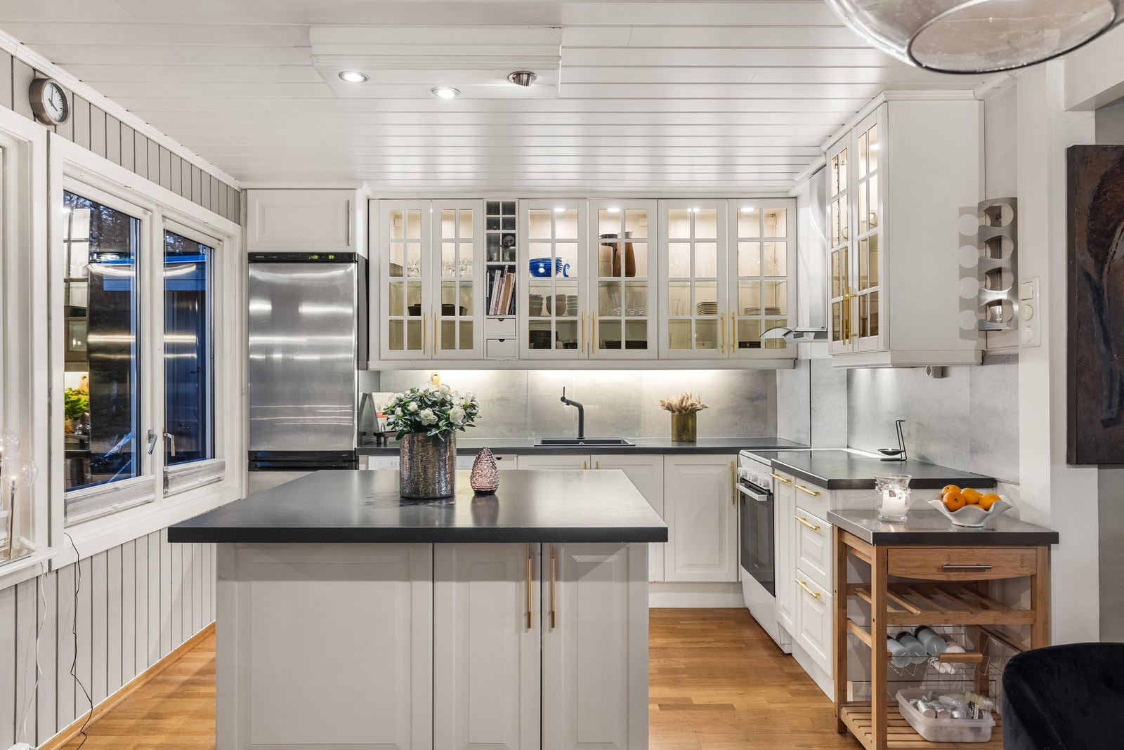 IKEA kjøkken med innredning fra 2006 som består av hvite profilerte fronter, 6 dører med glassfelt, lys/lyslist under overskap, kum med ettgreps blandebatteri, vifte til yttervegg over komfyr og opplegg for oppvaskmaskin. Galleribilde