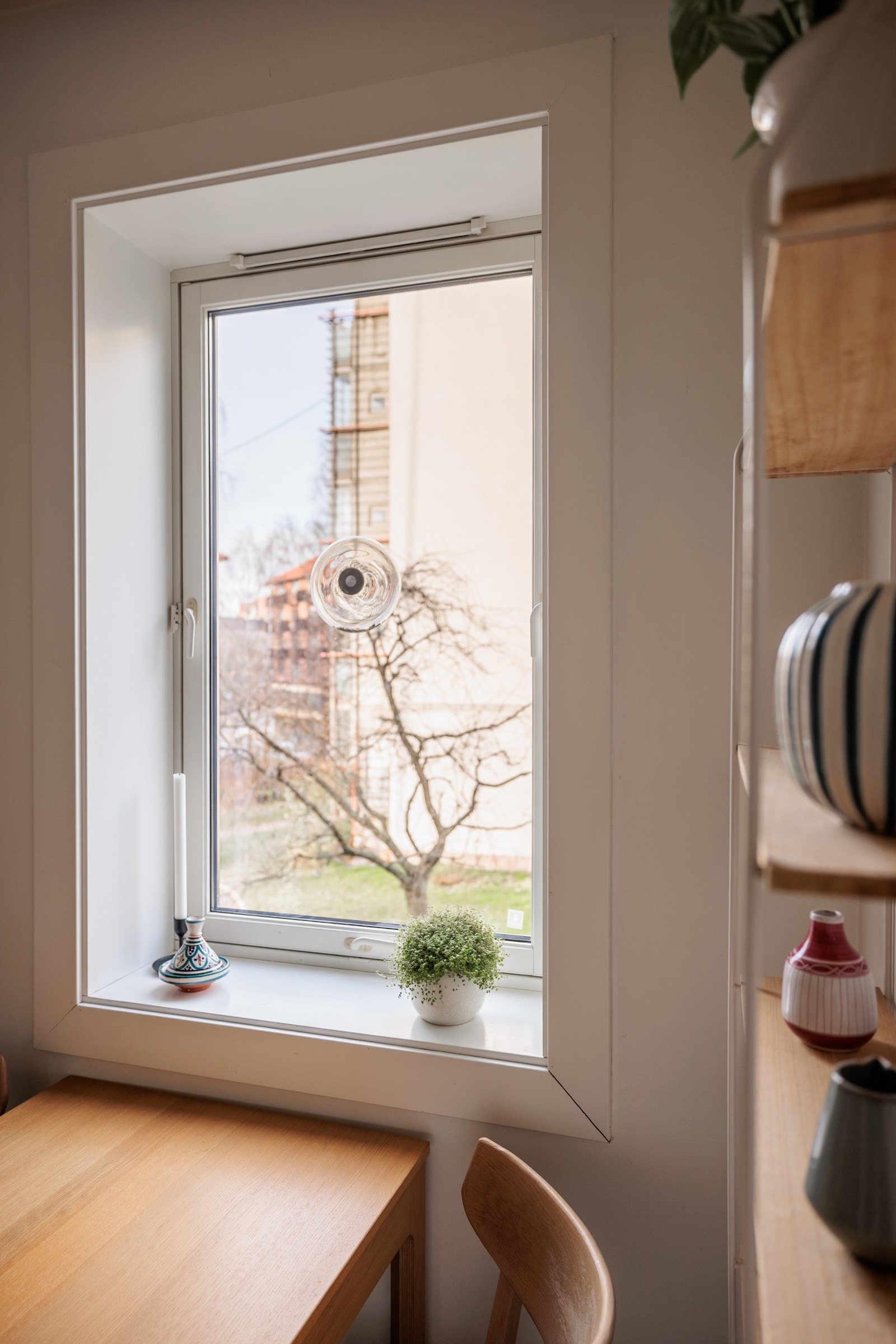 Ved vinduet er det plass til et spisebord som gjør at også kjøkkenet blir et naturlig oppholdsrom og samlingspunkt. Det er mørke fliser på gulv med gulvvarme og glatte lysmalte overflater. Galleribilde