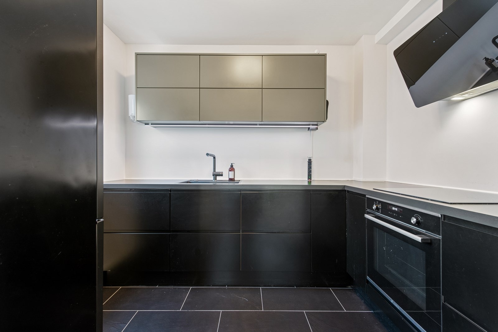 Kjøkkenet ligger i eget rom og ble totalrenovert i 2022 med sort innredning som gir et stilrent uttrykk. Galleribilde