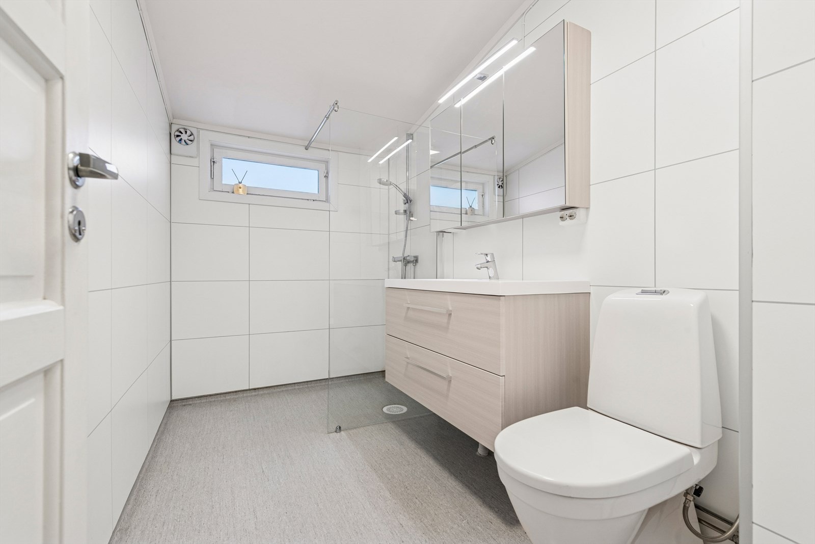 Pent og funksjonelt baderom med gulvbelegg og varmekabler, baderomsplater på vegger og malte, glatte flater i himling. Galleribilde