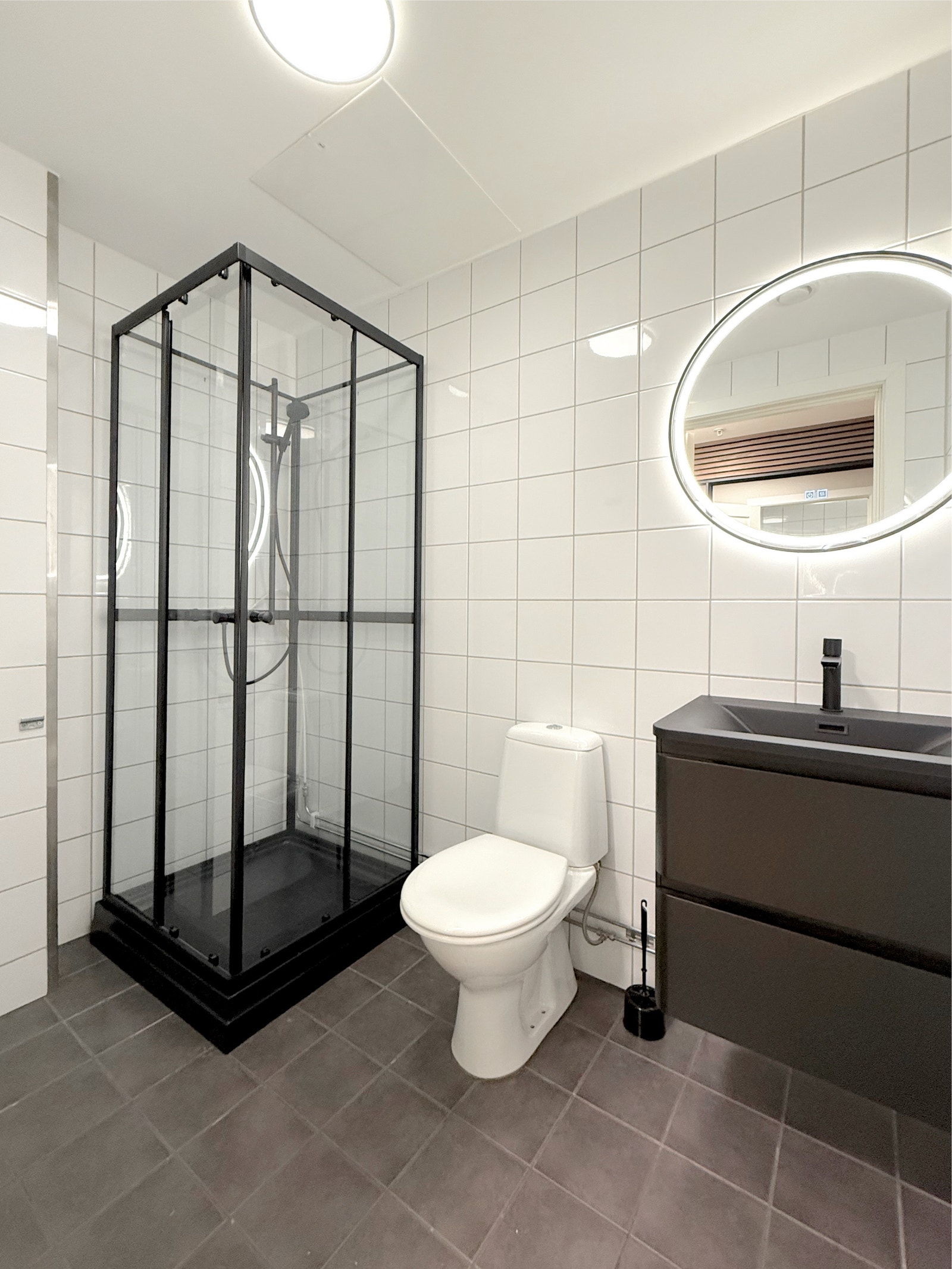 Badet sett fra en annen vinkel viser den romslige dusjen, toalettet og baderomsinnredningen med speil Galleribilde