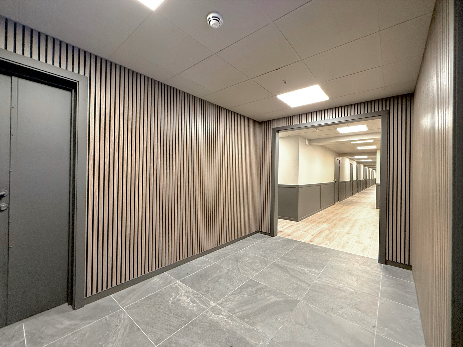 Pene fellesarealer med moderne trepaneler og flislagt gulv gir et godt førsteinntrykk før du går inn i leiligheten Galleribilde