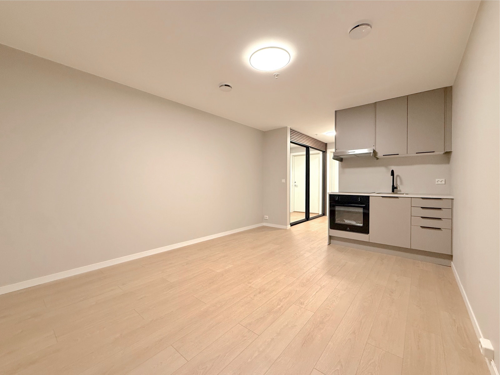 Åpen stue/kjøkkenløsning med lyse vegger og parkett. Rommet gir plass til både sofa, seng og spisebord. Galleribilde