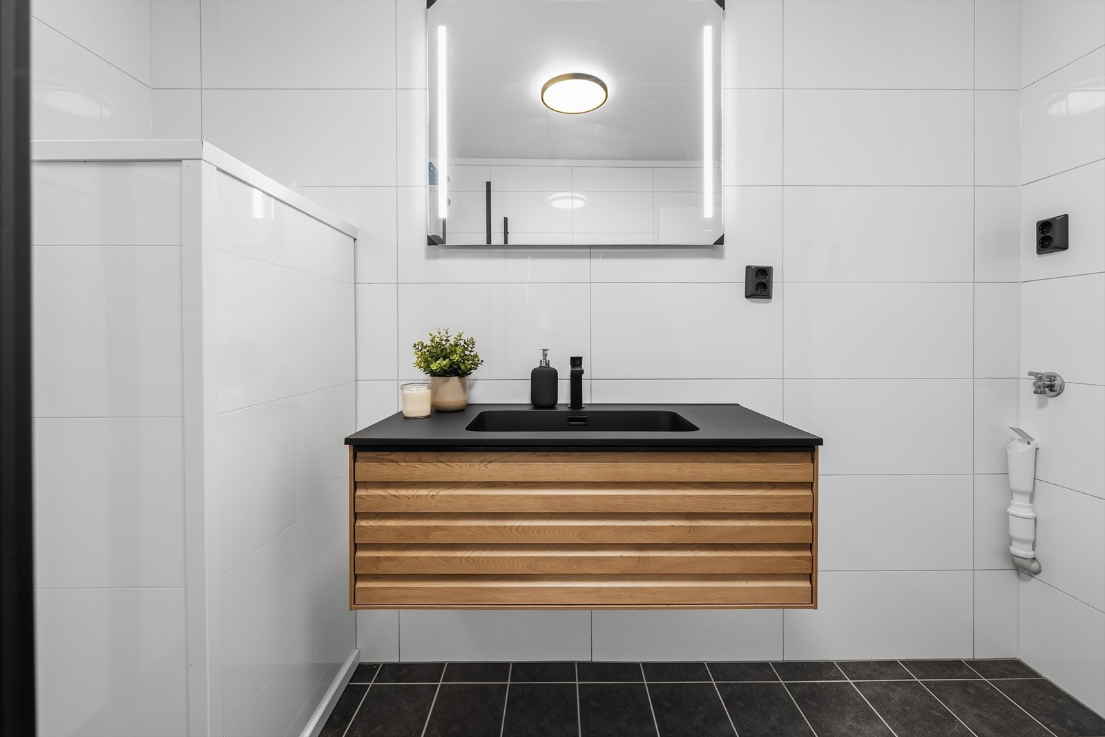 Lekker innredning med spilefronter og sort heltrukket servant og blandebatteri. Opplegg for vaskemaskin. Galleribilde