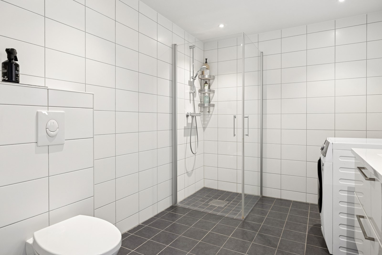 Rommet er innredet med baderomsinnredning med servant, speil, lys, dusjhjørne med glassdører, vegghengt toalett og opplegg for vaskemaskin. Galleribilde