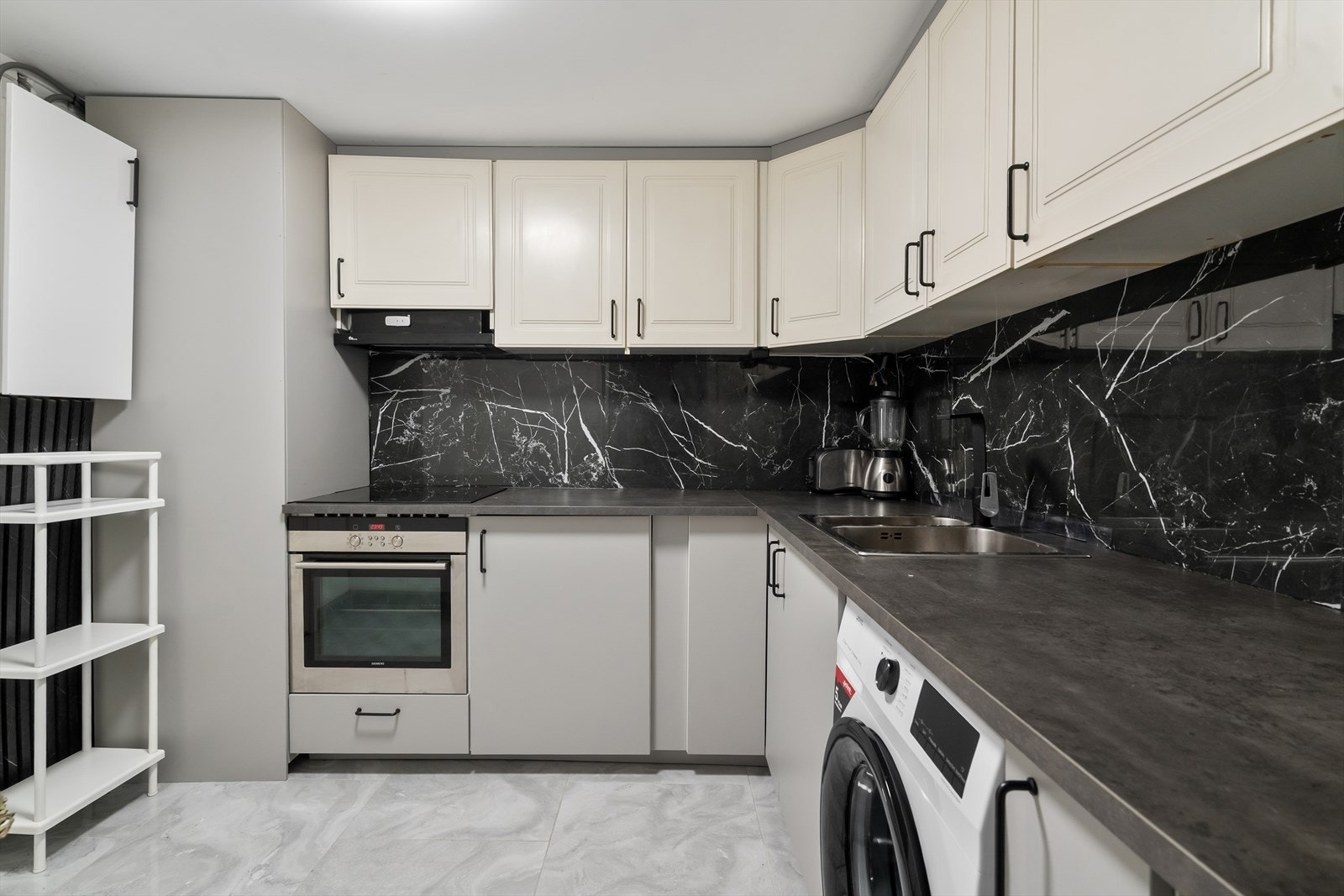 Enkelt velholdt kjøkken med opplegg til vaskemaskin m.m. i u.etg. Galleribilde