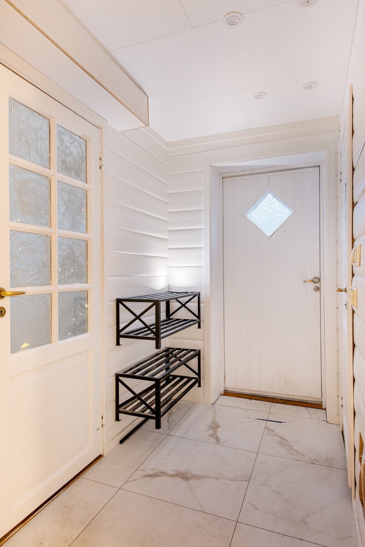 Inngangsparti underetasjen. Flislagt gulv. Downlights i taket. Dør med frostet glass til stue/soverom ca. 10 kvm. Galleribilde