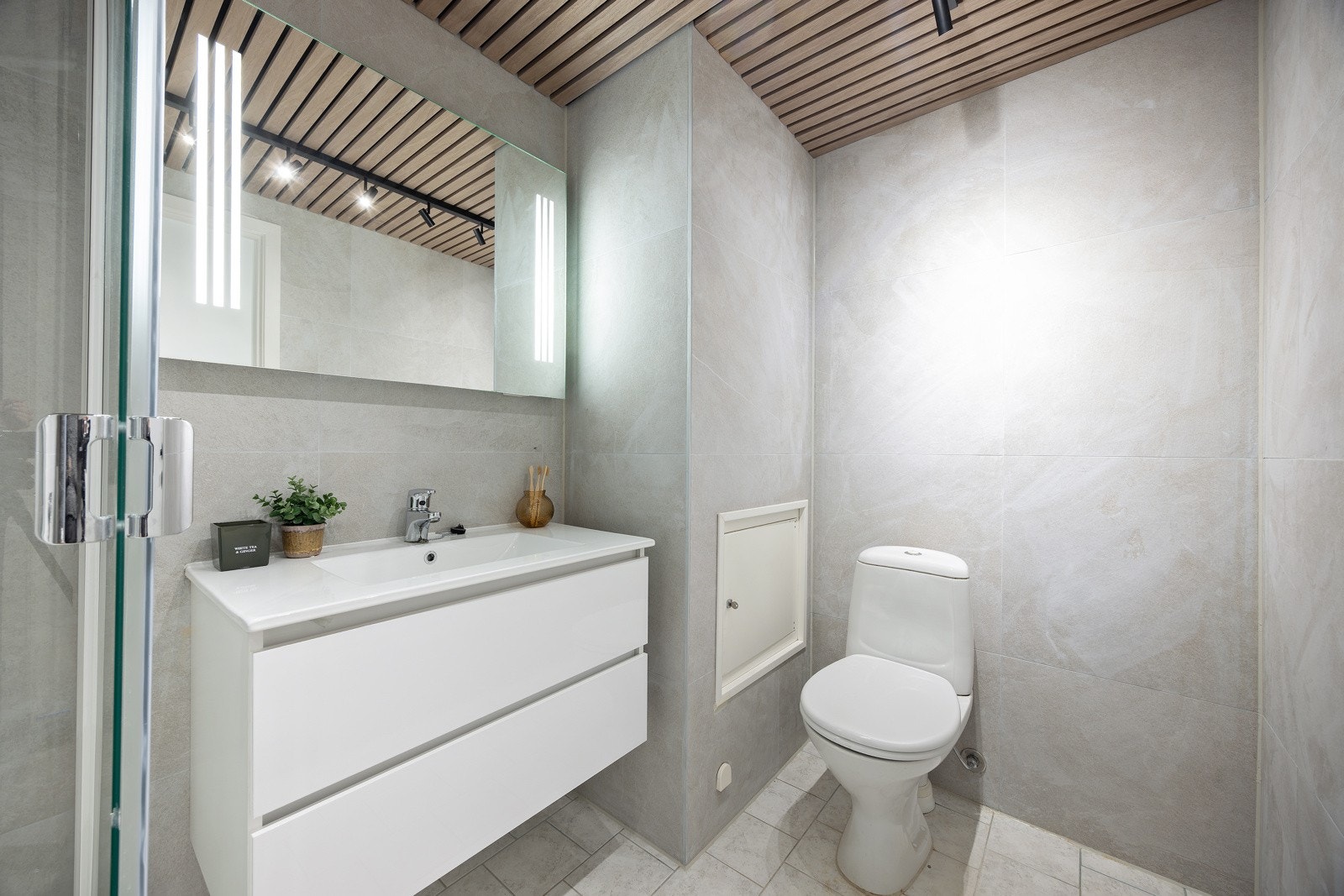 Lyst og delikat bad med flis på gulv og vegger, eikespiler i tak, varmekabler, spotteskinne i tak og avtrekk til sentralt ventilasjonsanlegg. Galleribilde