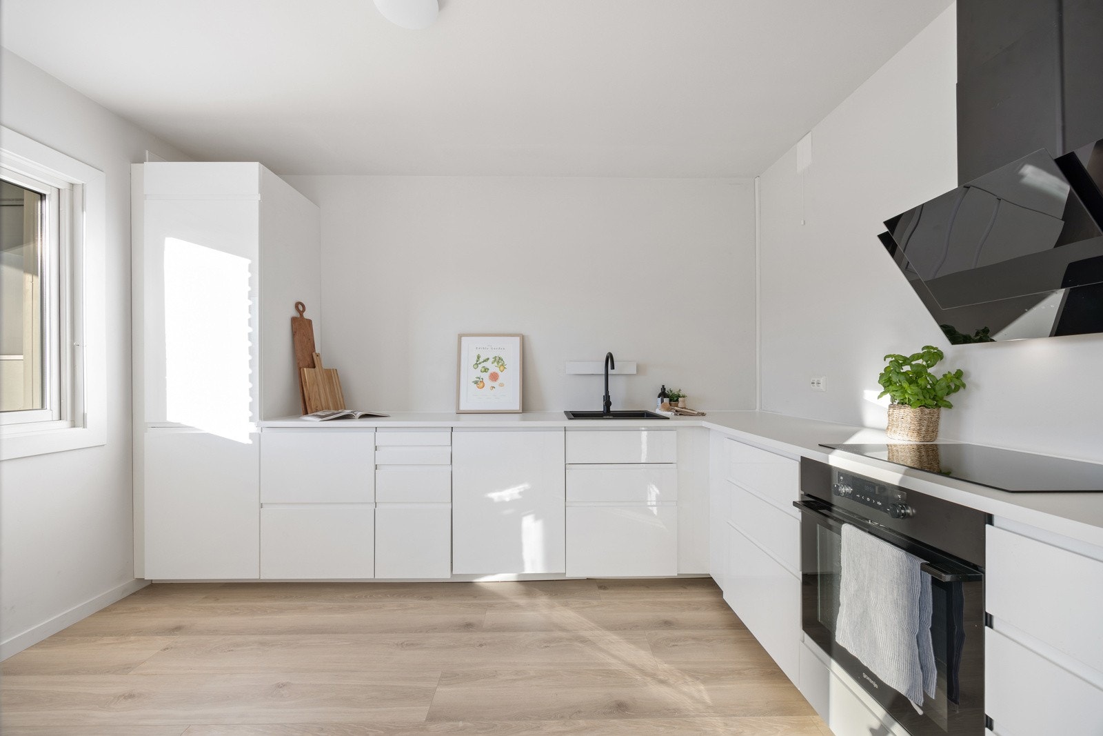 Lyst og moderne kjøkken med glatte fronter og laminatbenkeplate. Galleribilde