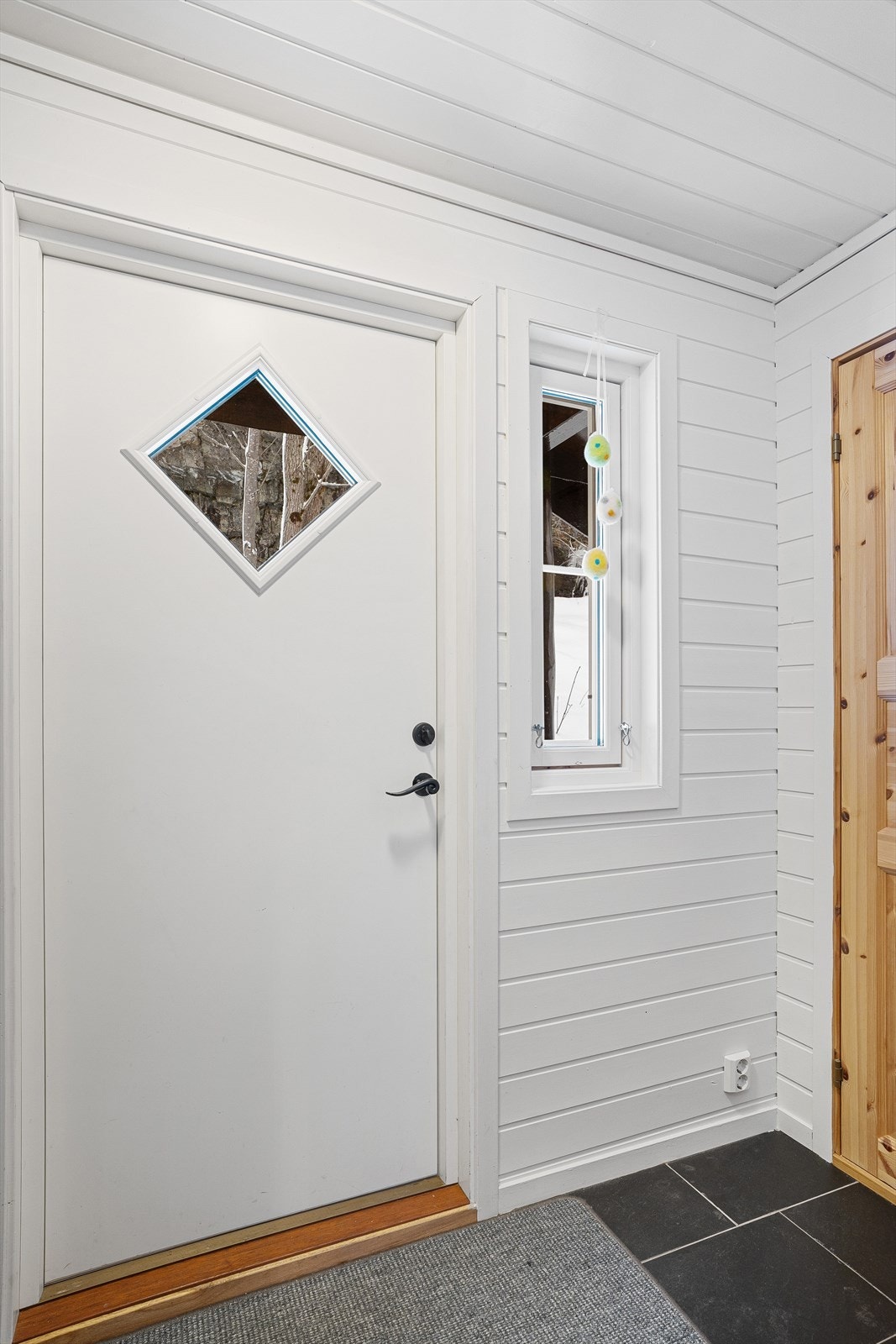 Romslig entré med flislagt gulv og god plass til å henge av seg yttertøy Galleribilde