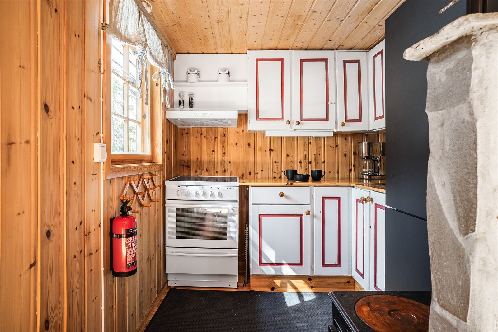 Kjøkkenet har åpen løsning fra stuen. Her er det malt trekjøkken med rette profilefronter. Det er ventilator over komfyr og rom for kjøl-/fryseskap. I rommet står også en vedovn. Galleribilde