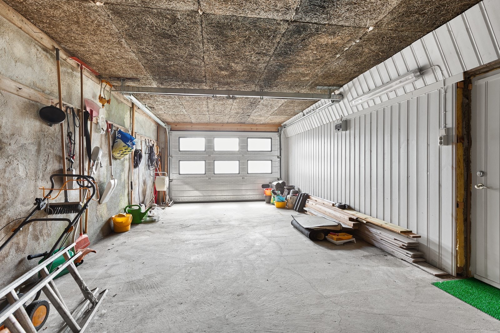 Garasjen har leddport og plass til to biler. Det er isolert ytterdør inn til bolig. Galleribilde